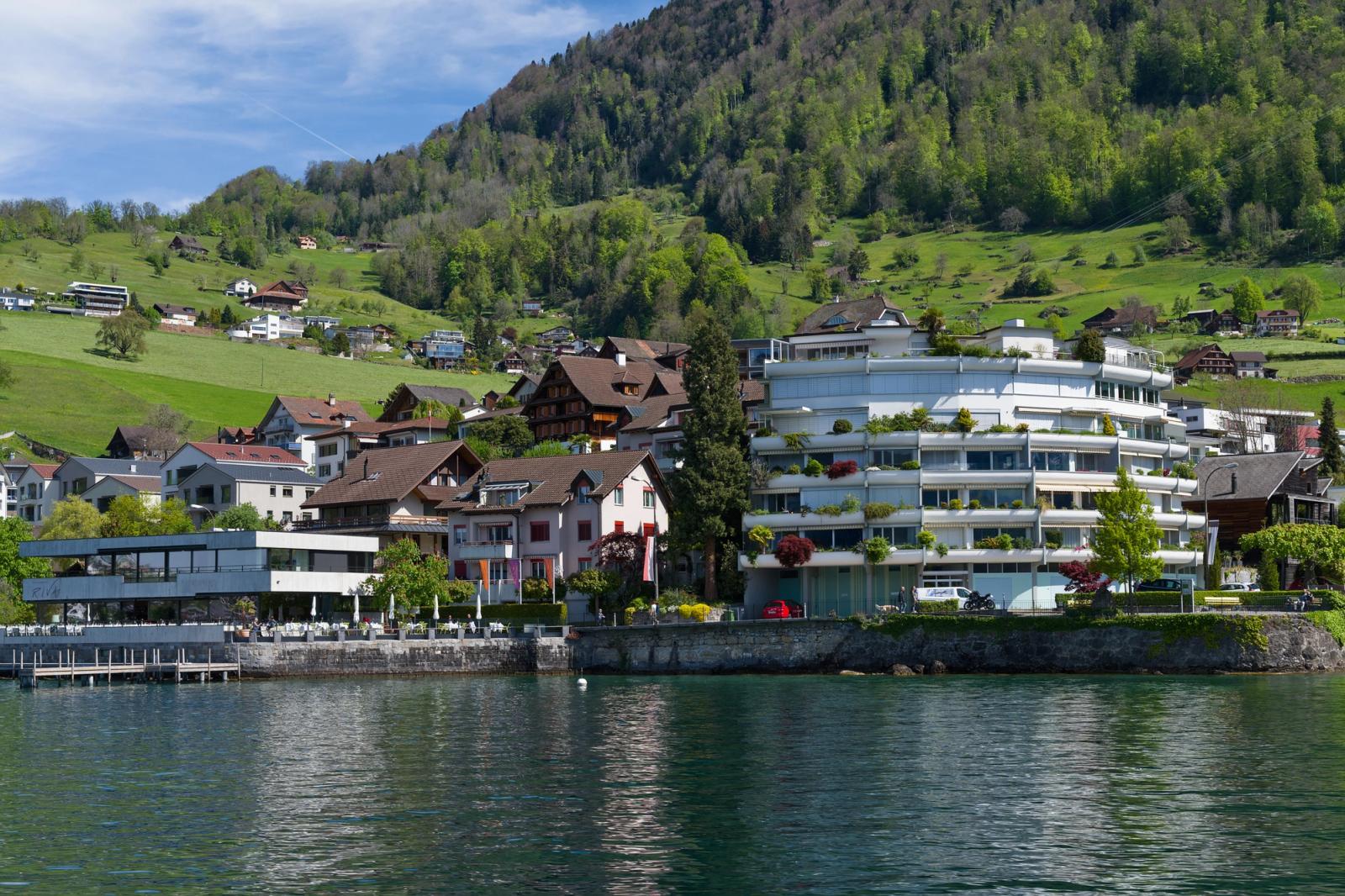 A picturesque view of lakeside buildings and lush hills in Vitznau, Switzerland