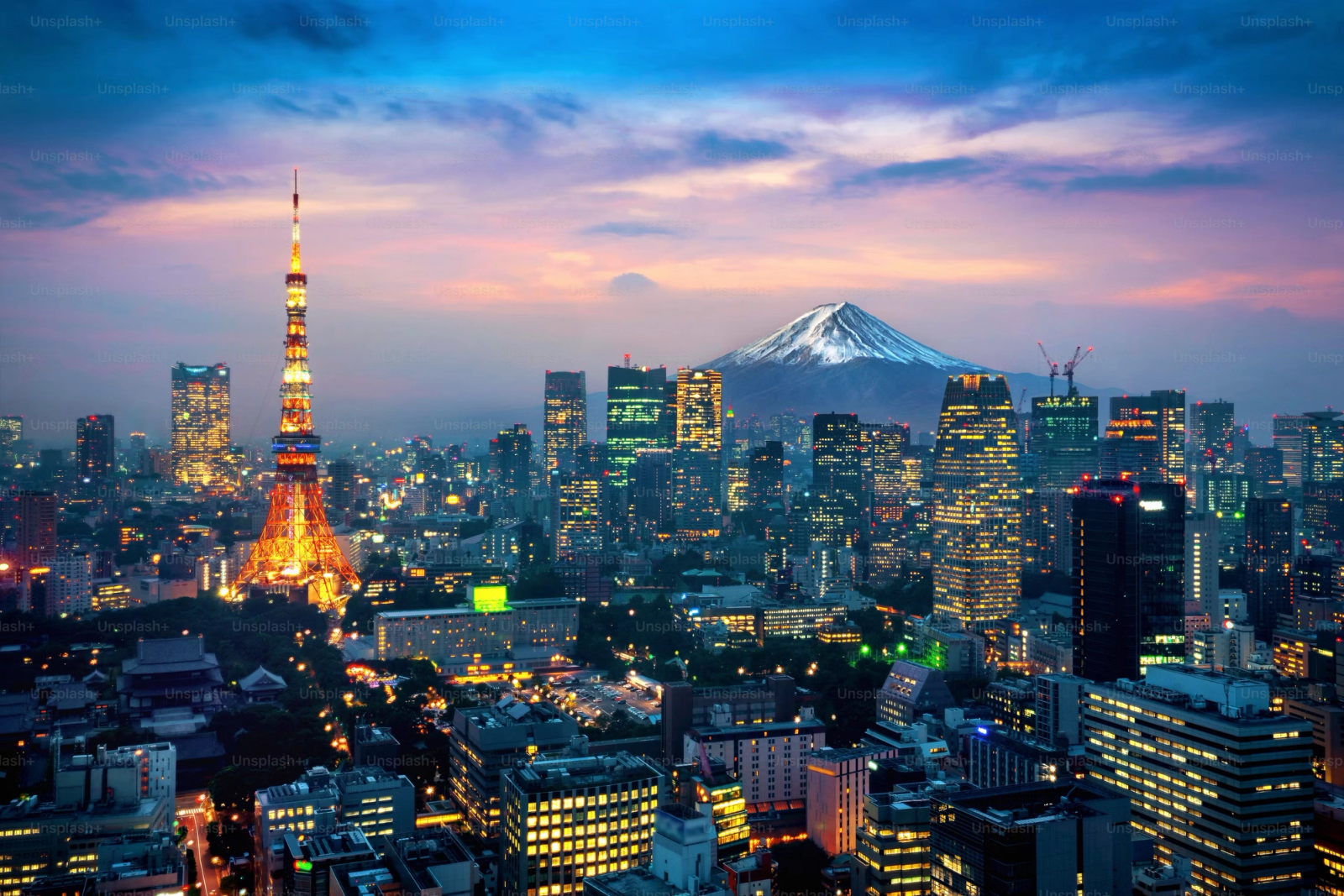 Tokyo Tower lit up at dusk with a snow-capped volcano on the horizon