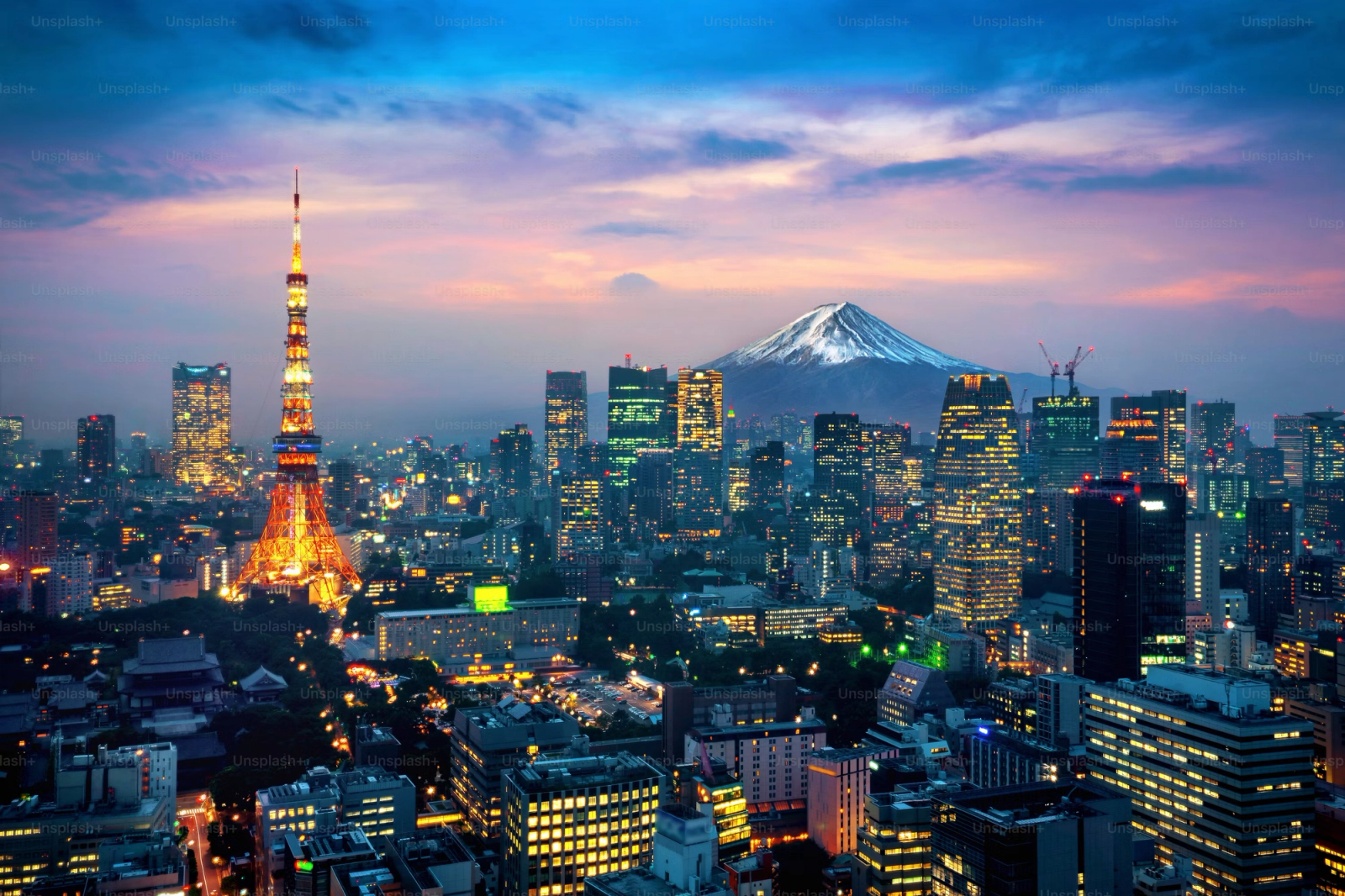 Tokyo Tower lit up at dusk with a snow-capped volcano on the horizon
