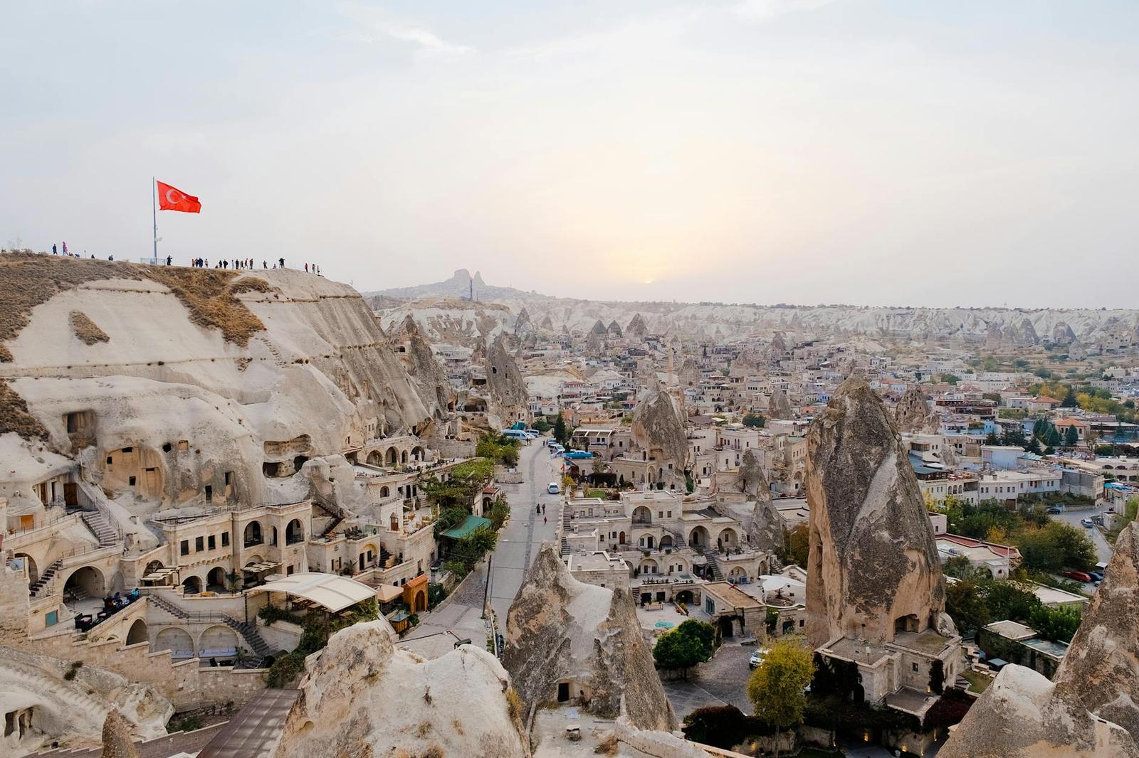 Cave dwellings carved into cone-shaped rock formations above a valley town