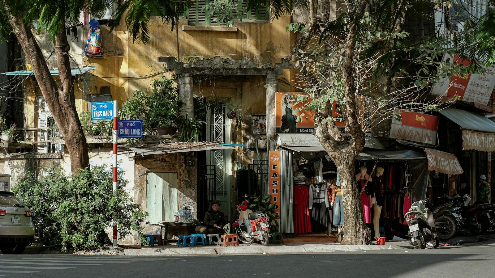 Street corner boutique beneath a stone archway shaded by old trees