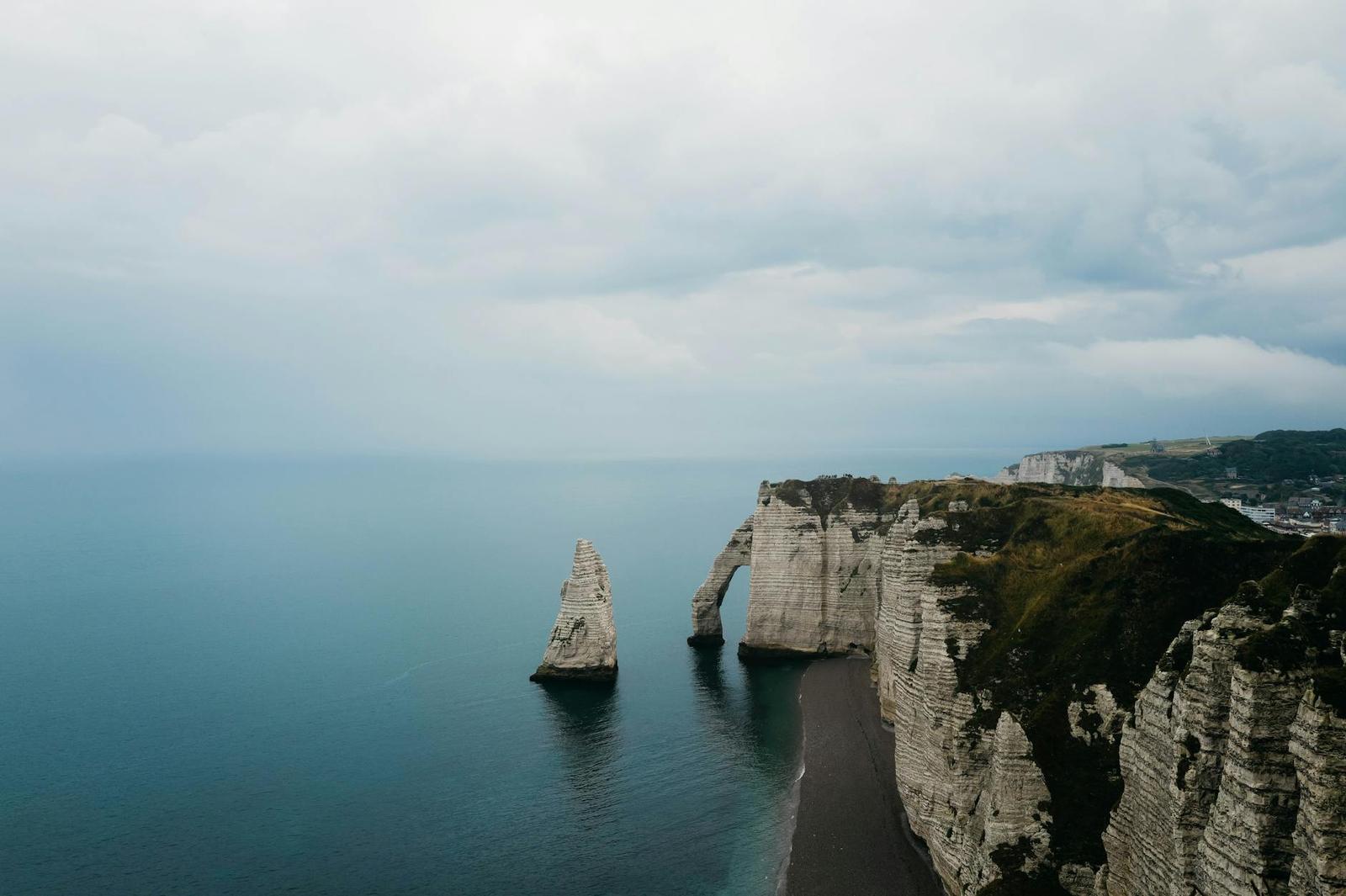 Chalk sea cliffs with a natural arch and needle rock formation