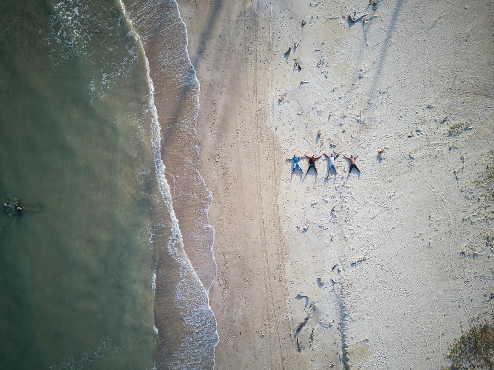 An aerial view of a beach with people resting near the surf