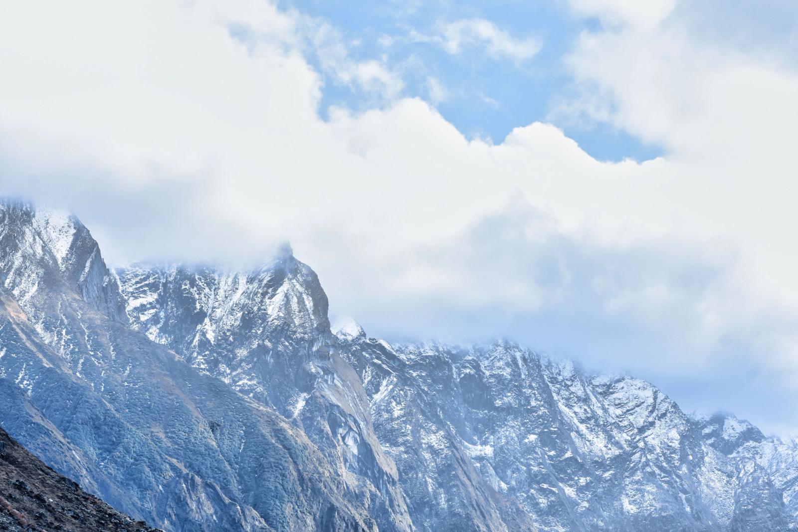 Majestic snow-covered mountains of Kedarnath, India, under a cloudy sky, showcasing natural beauty and rugged terrain