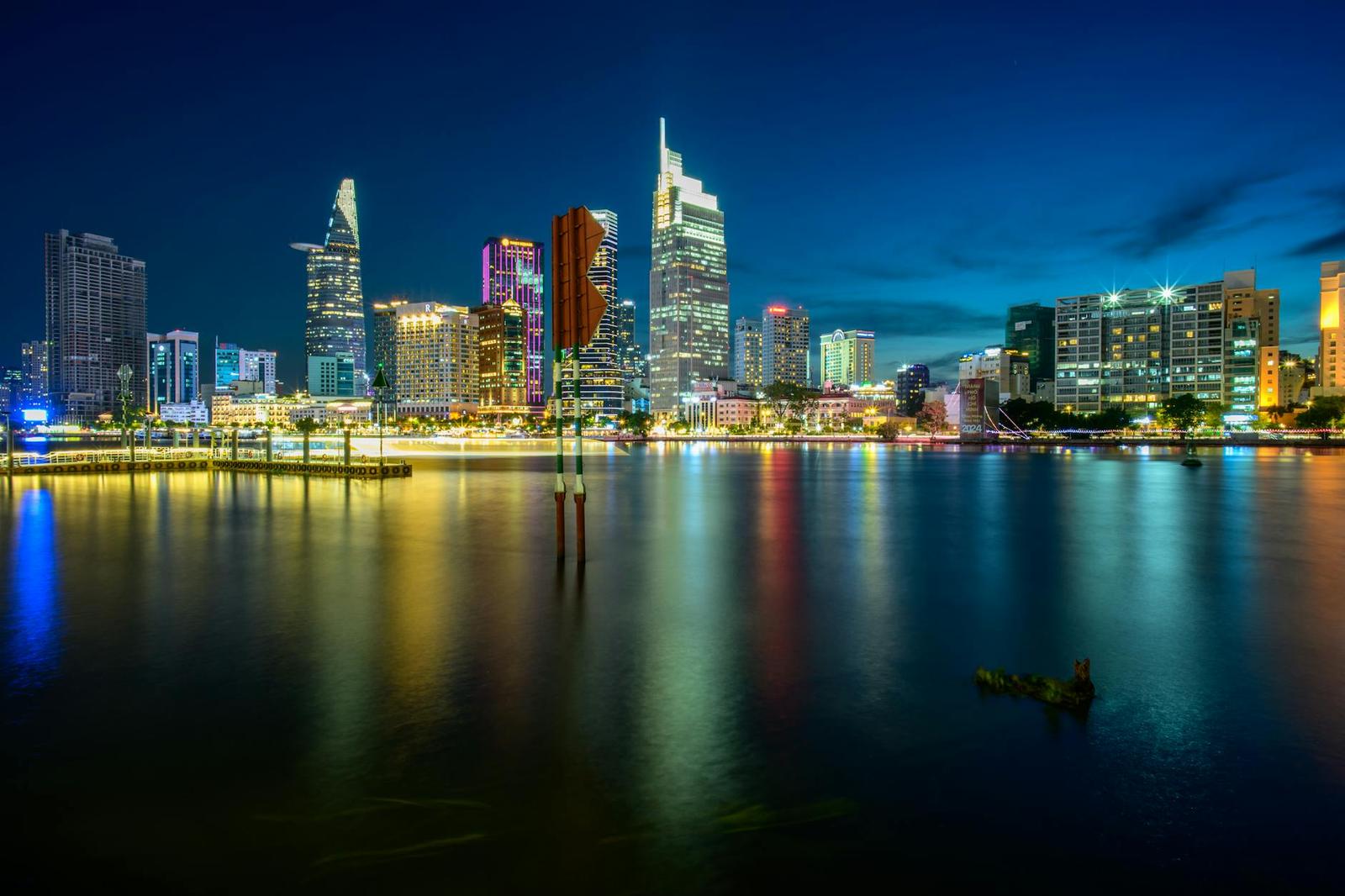 City skyline glowing over the water at dusk with a small boat