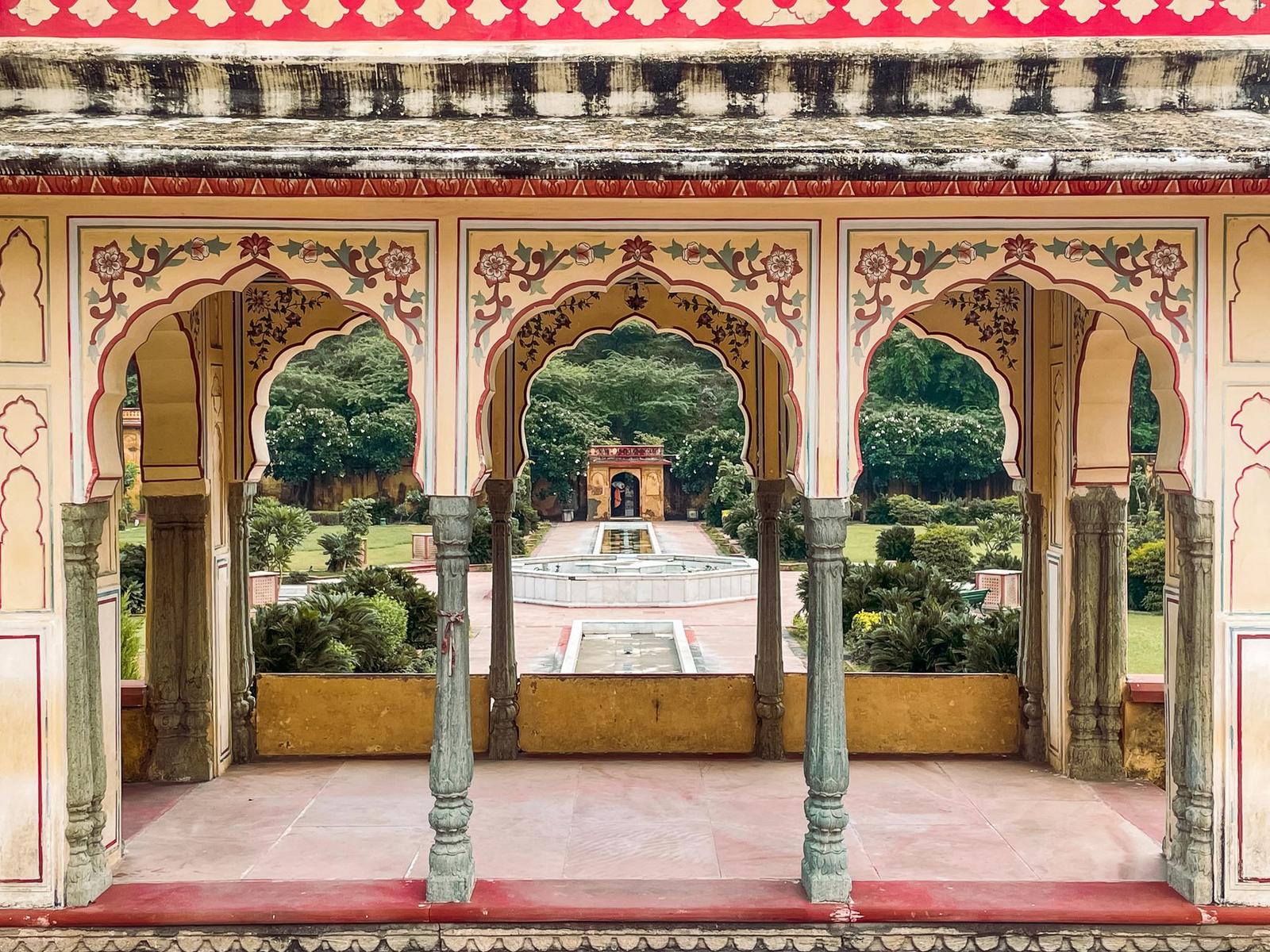 View through a painted arched pavilion toward a formal garden path