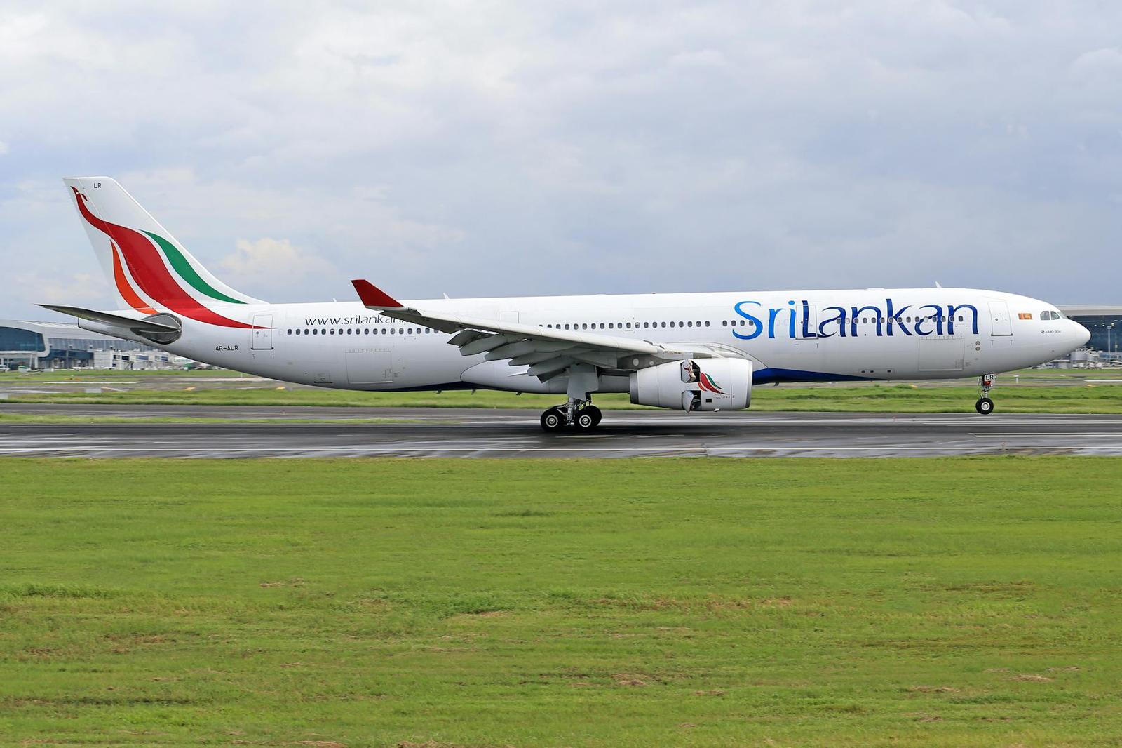 A white passenger jet taxiing on an airport runway beside green grass