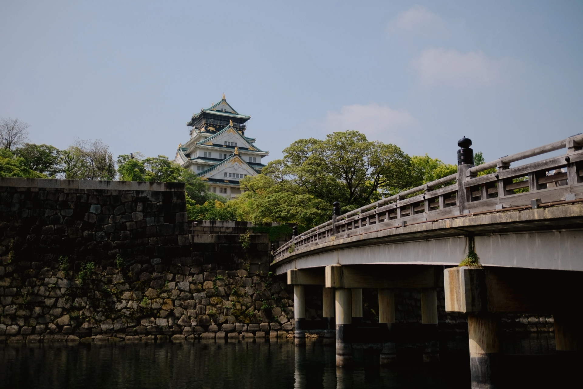 A picturesque view of Osaka Castle and nearby bridge surrounded by lush greenery