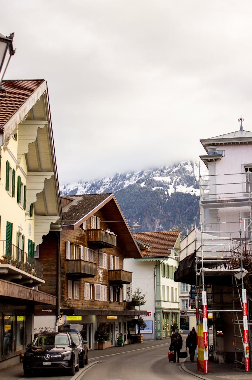 Traditional wooden chalets on a village street below a misty mountain