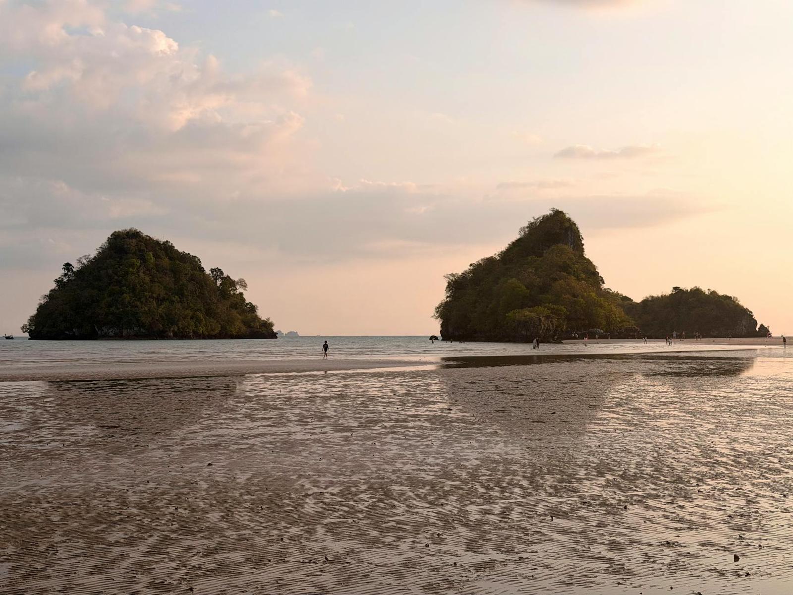 Two rocky islets rise from a tidal beach beneath a pastel evening sky