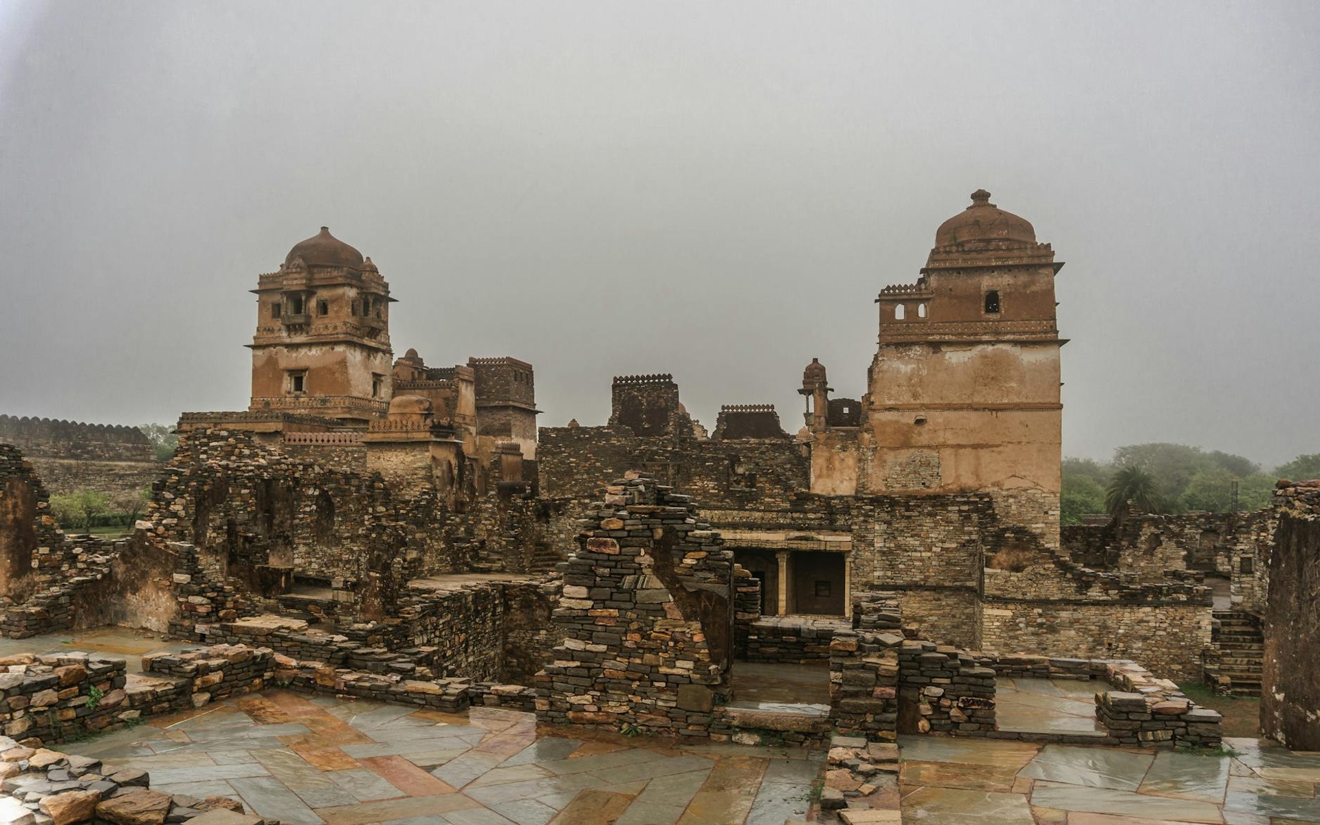 Weathered stone fort ruins with twin towers under a misty grey sky