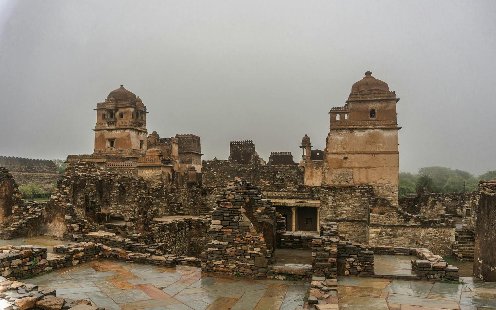 Weathered stone fort ruins with twin towers under a misty grey sky