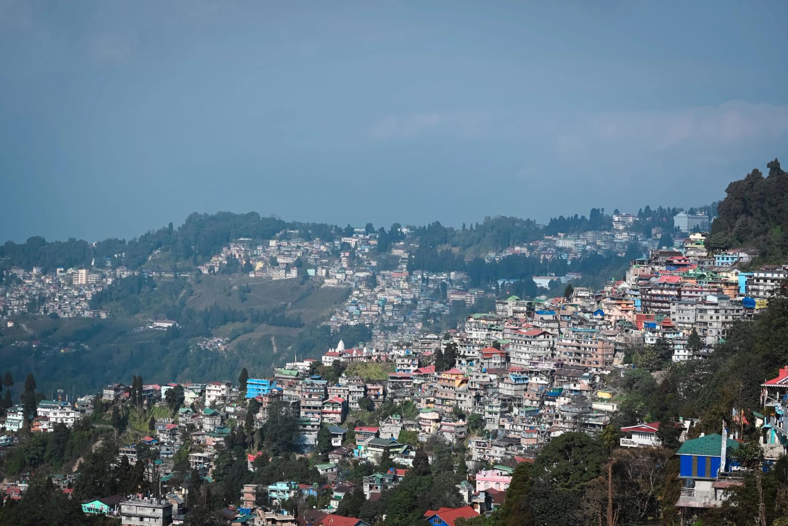 A picturesque view of a vibrant hill town in India with colorful buildings against a mountainous backdrop