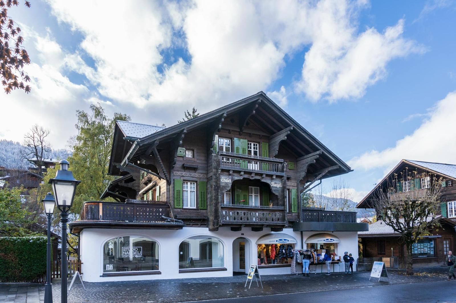 Traditional dark-timber chalet with green shutters and ground-floor shopfronts