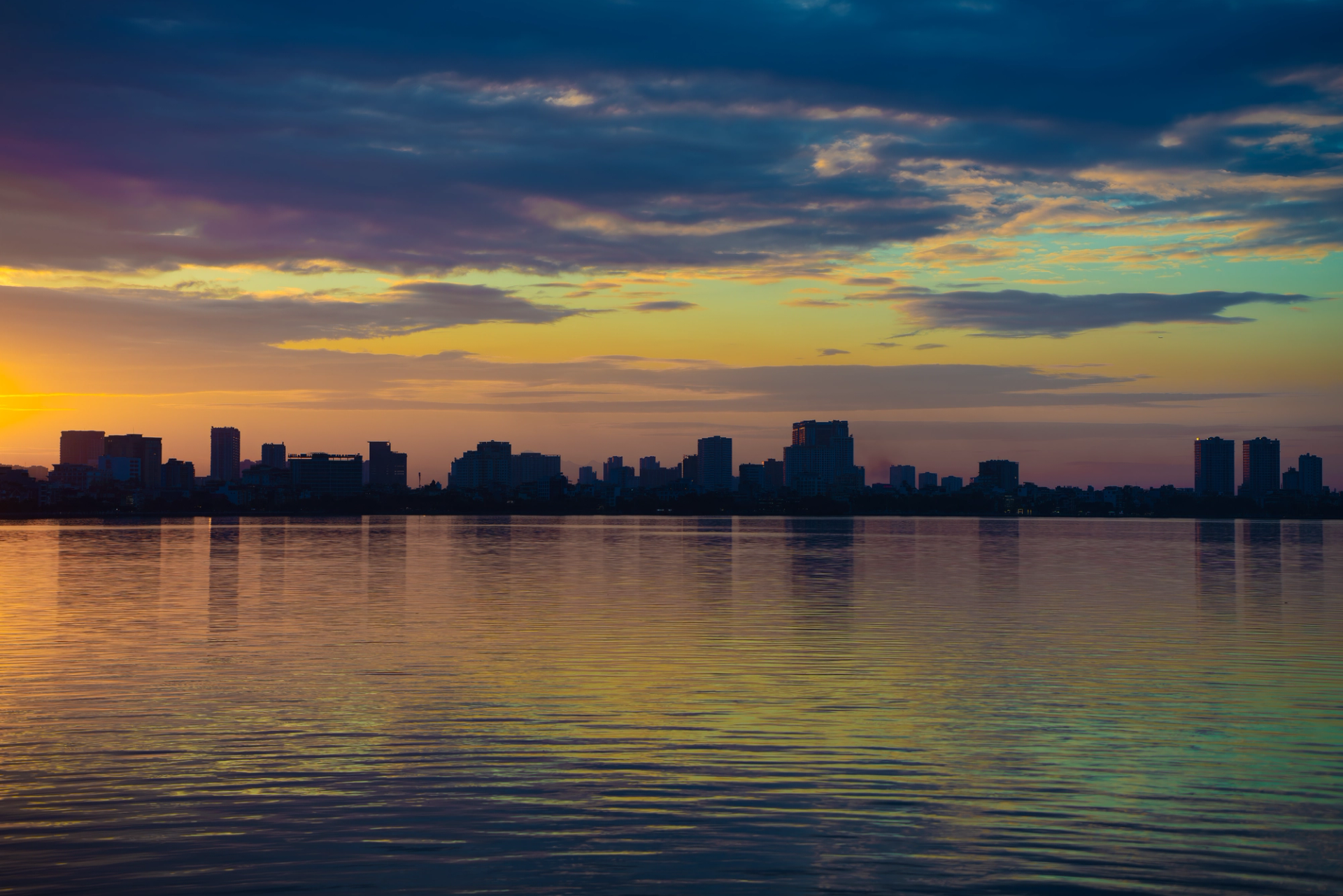 A stunning view of Hanoi's skyline reflecting on a calm lake during sunrise