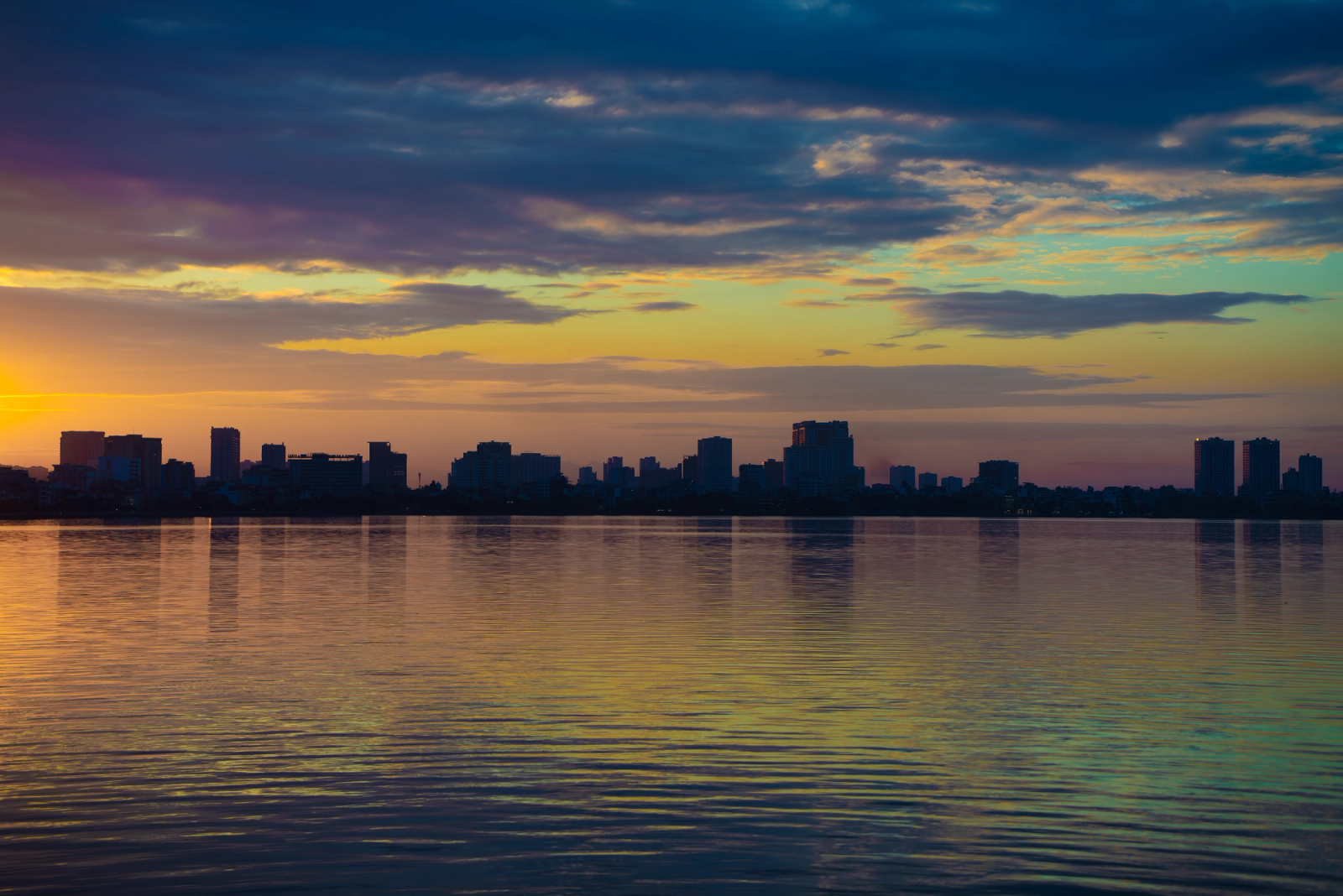 A stunning view of Hanoi's skyline reflecting on a calm lake during sunrise