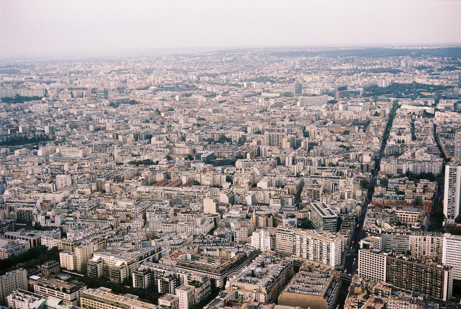 Expansive aerial view of Paris displaying dense urban architecture and skyline from above