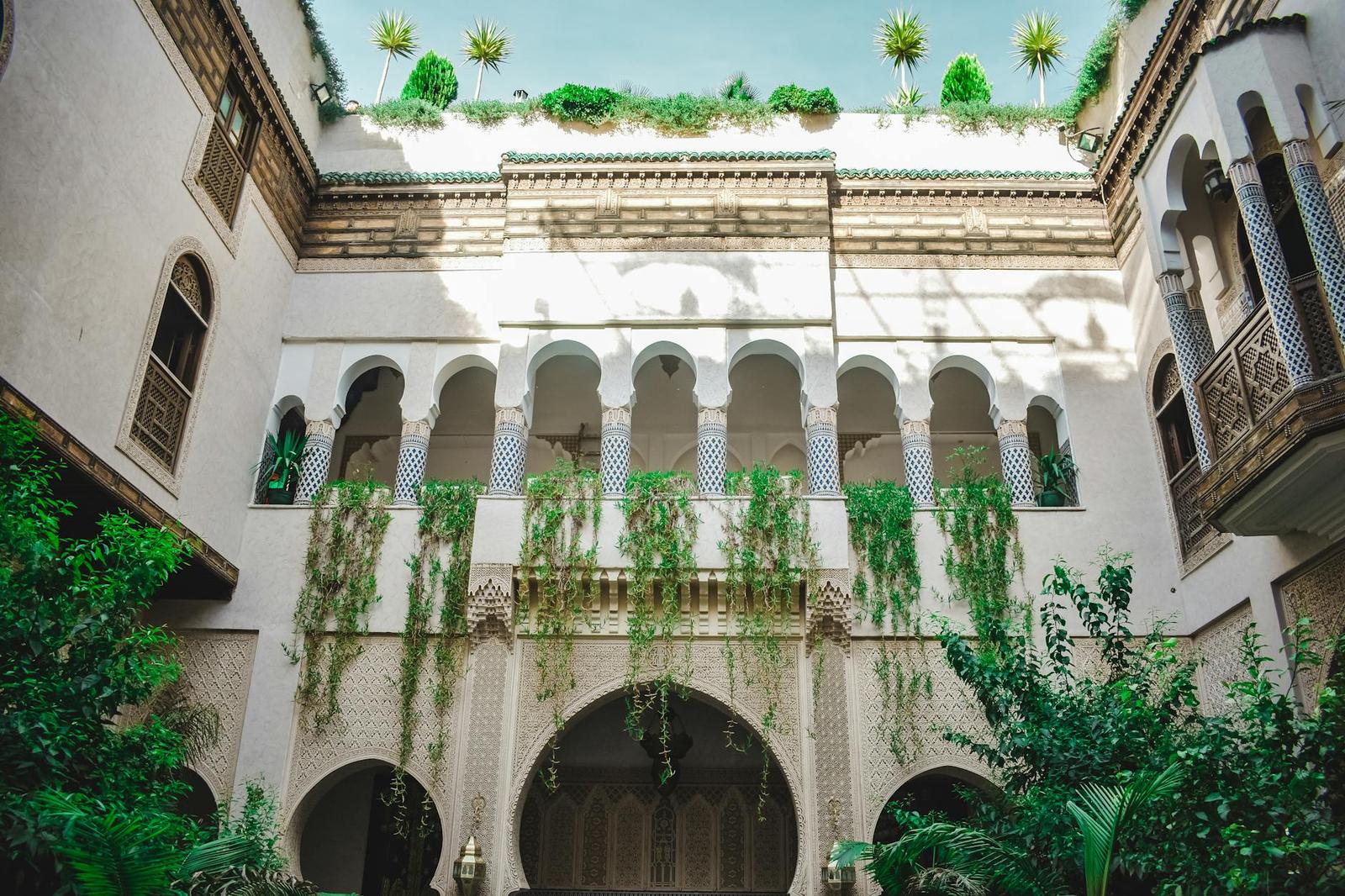 An arched courtyard facade draped in greenery below a rooftop garden