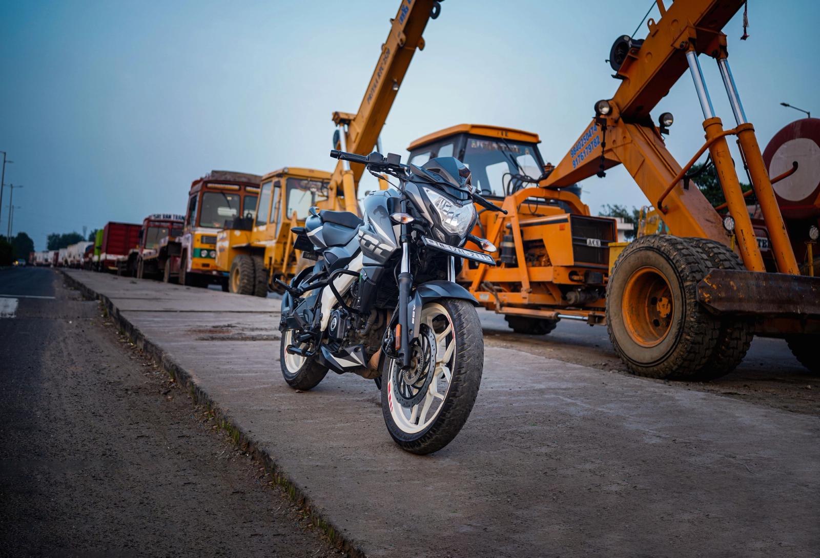 Motorcycle parked on an urban street with construction vehicles in Chennai, India