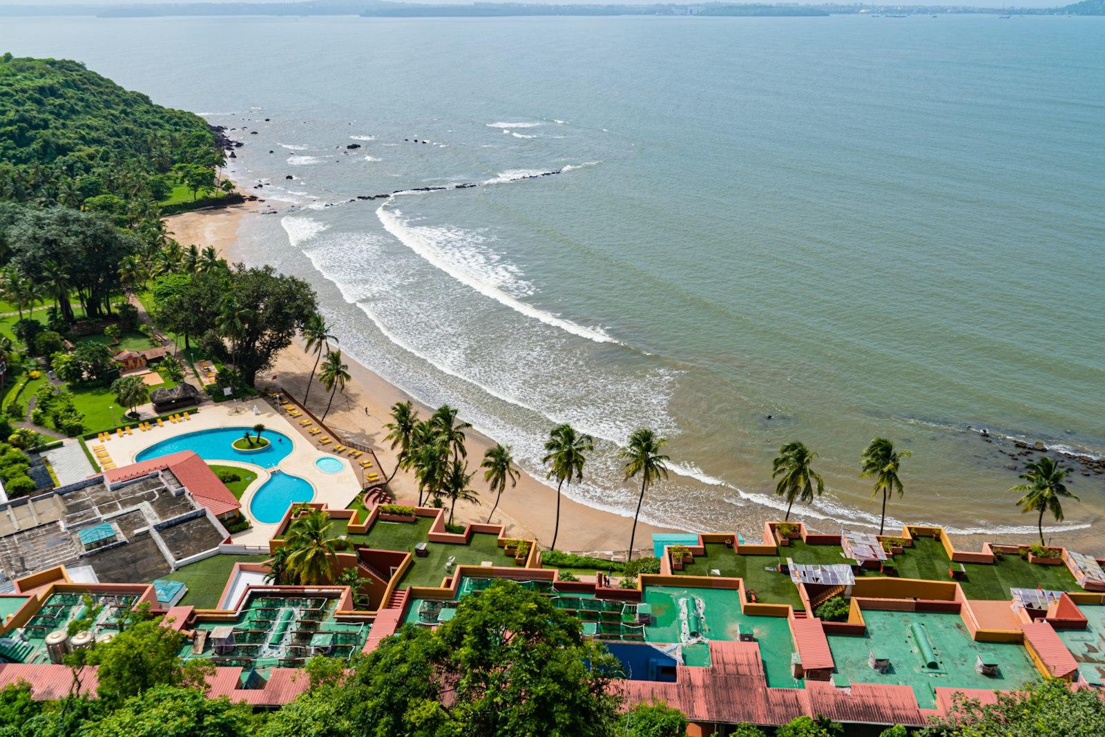 A cove resort with pools above a palm-lined beach