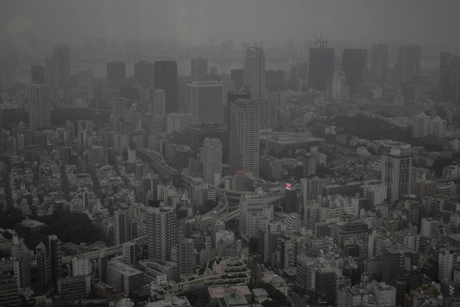 A hazy high-rise skyline stretching to the horizon under grey skies