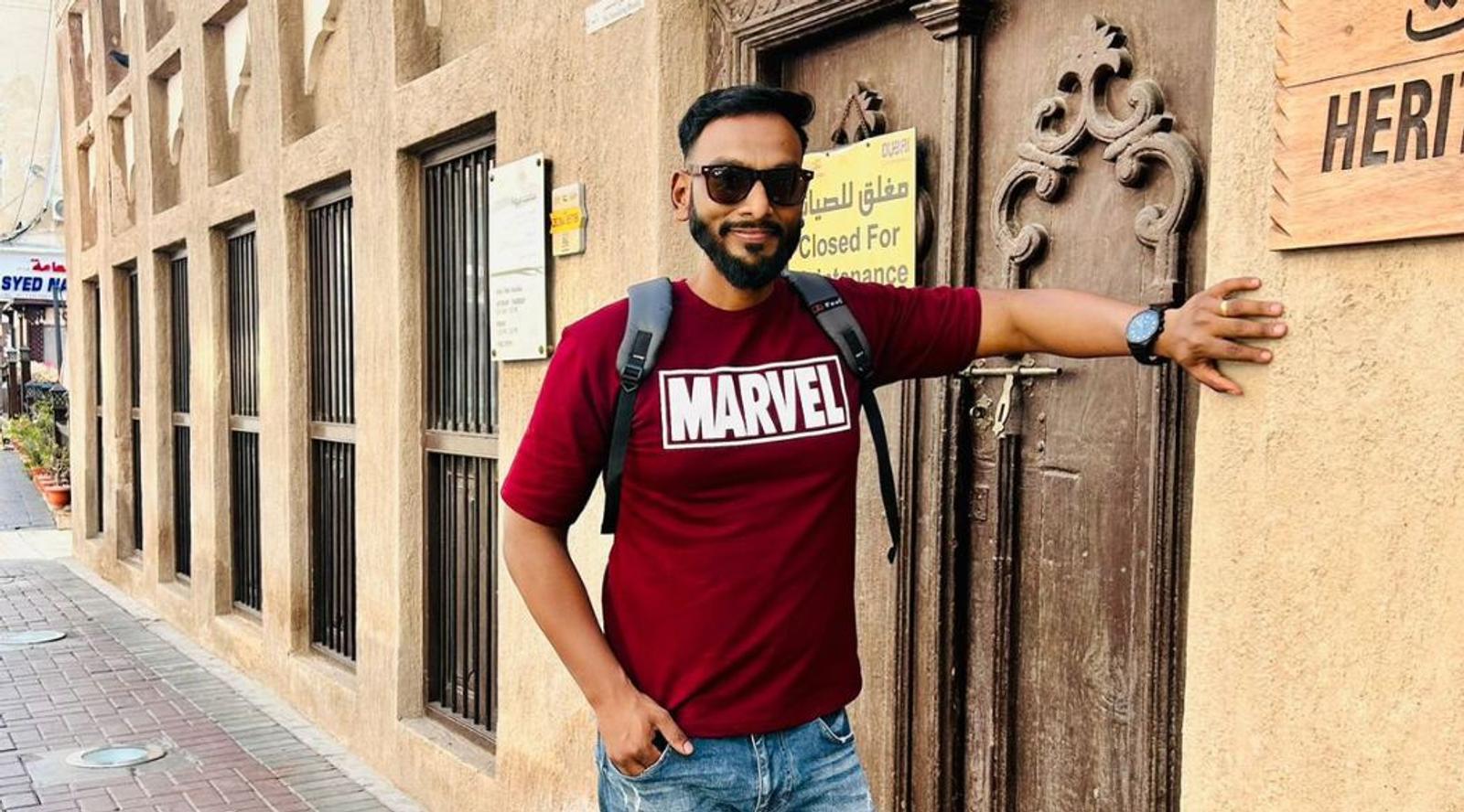 A man wearing a red "MARVEL" t-shirt poses