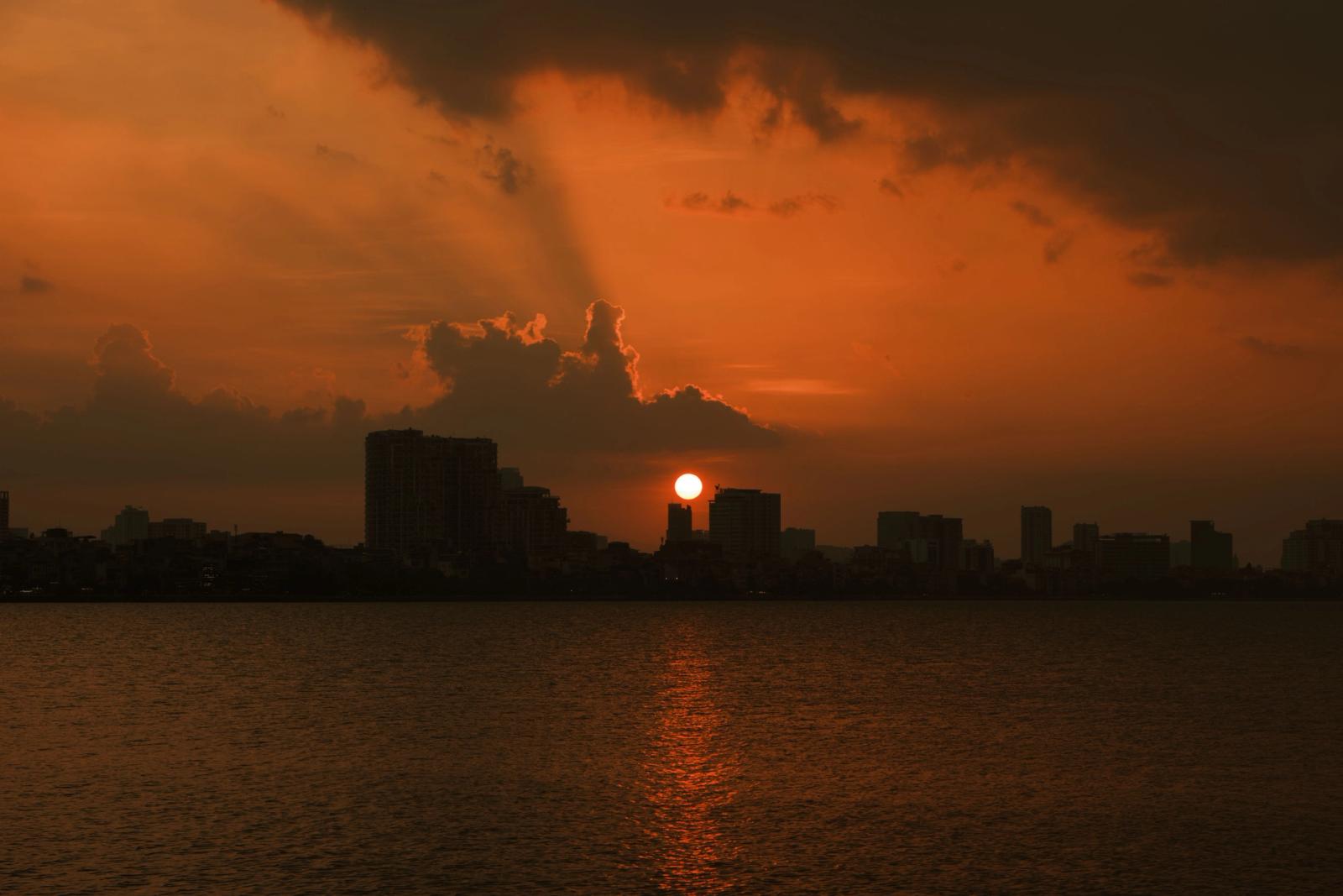 Breathtaking sunset over Hanoi's urban skyline with vibrant autumn hues reflecting on the water