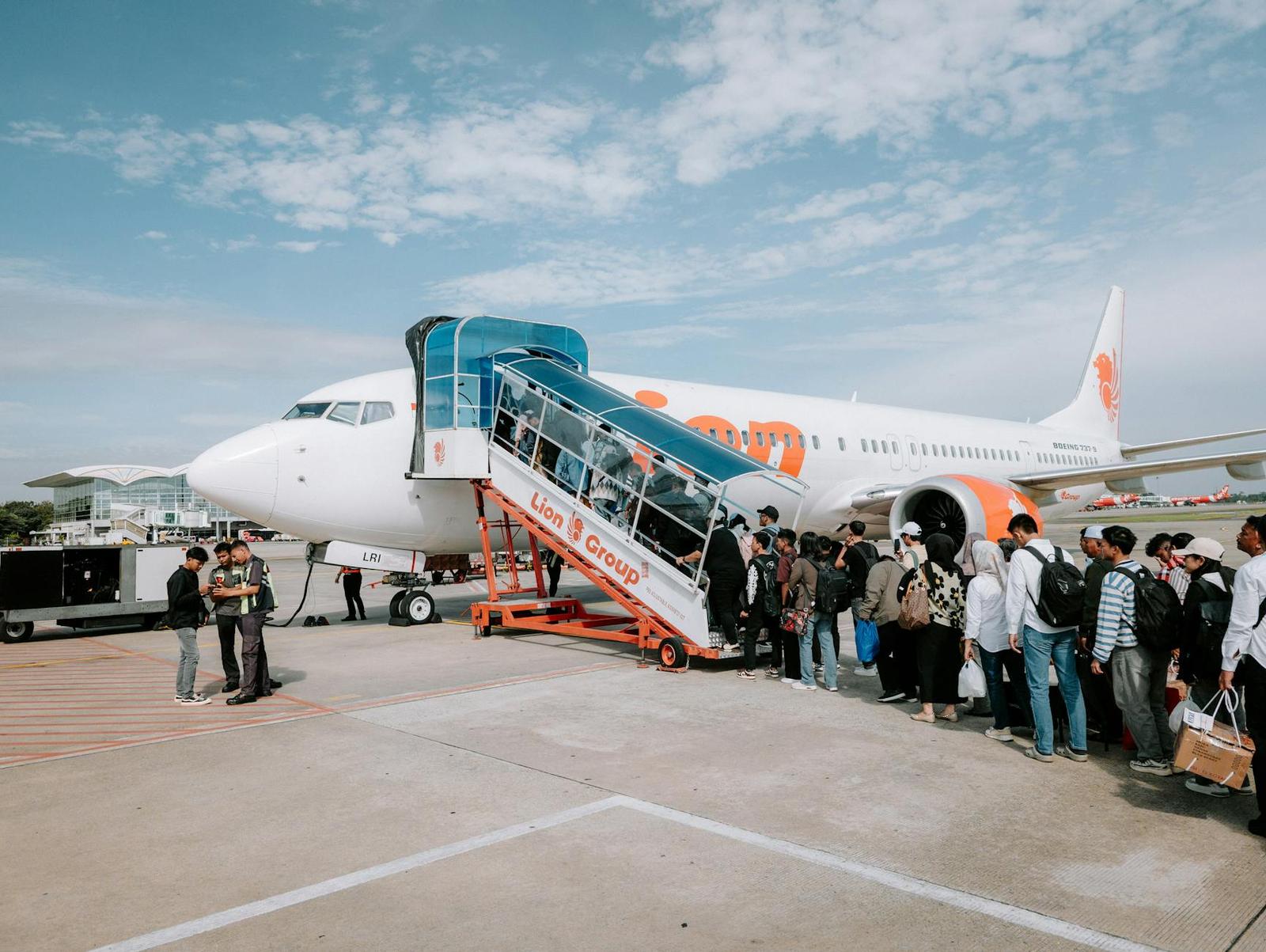 Passengers queue to board an airplane via mobile stairs on the tarmac