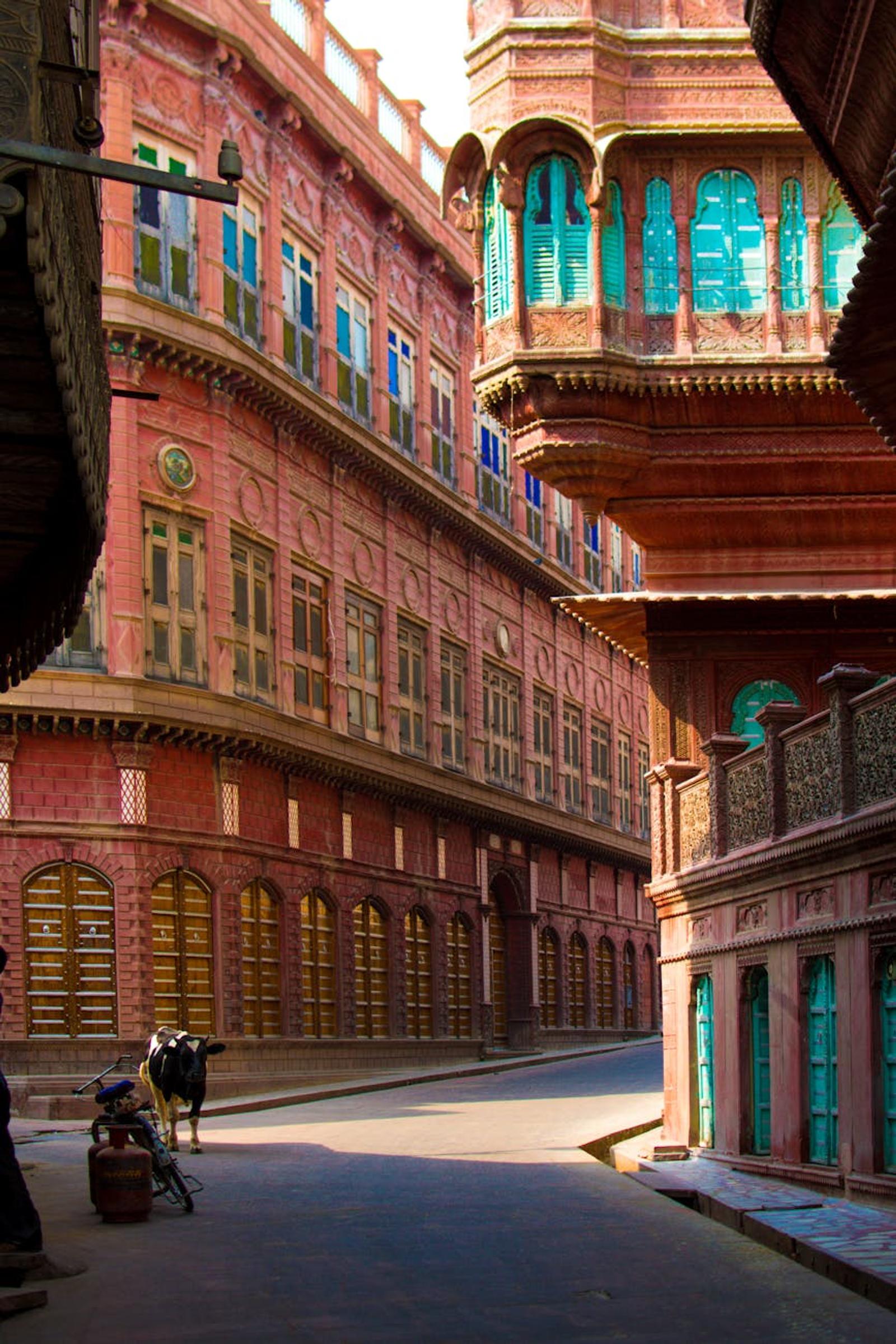 A vibrant street showcasing the historic architecture of Bikaner, India, with pink sandstone buildings