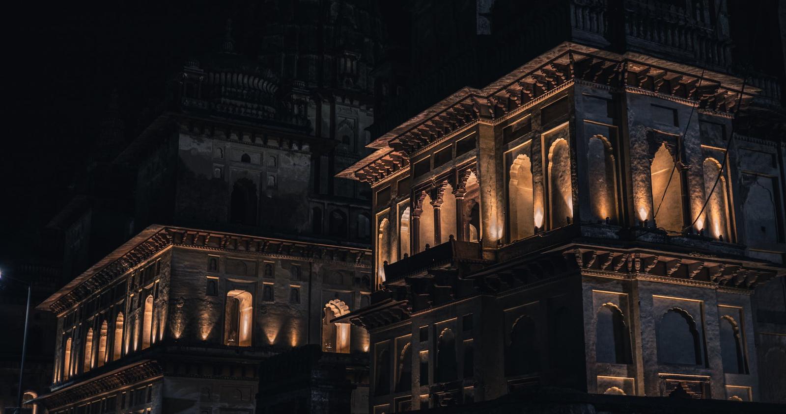 Illuminated stone palace towers against a dark night sky
