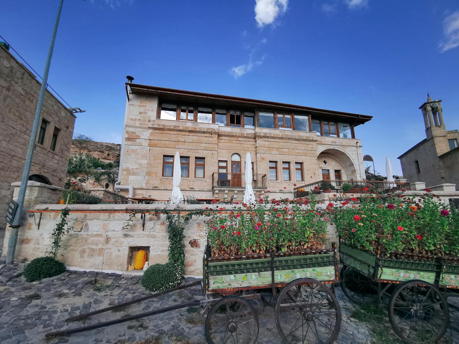 Stone hotel building with rows of arched windows behind flower-filled carts