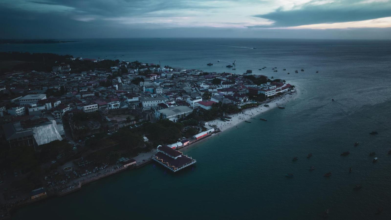 Aerial dusk view of a coastal town with a jetty extending into calm water