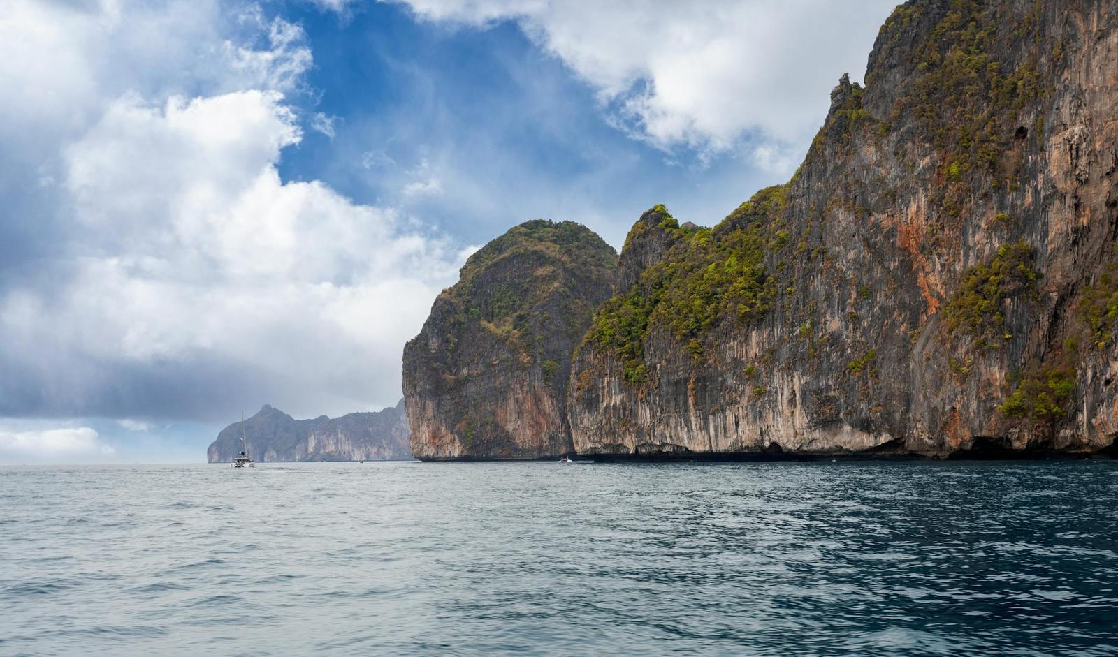 Breathtaking view of limestone cliffs towering over a tranquil sea under a vibrant sky