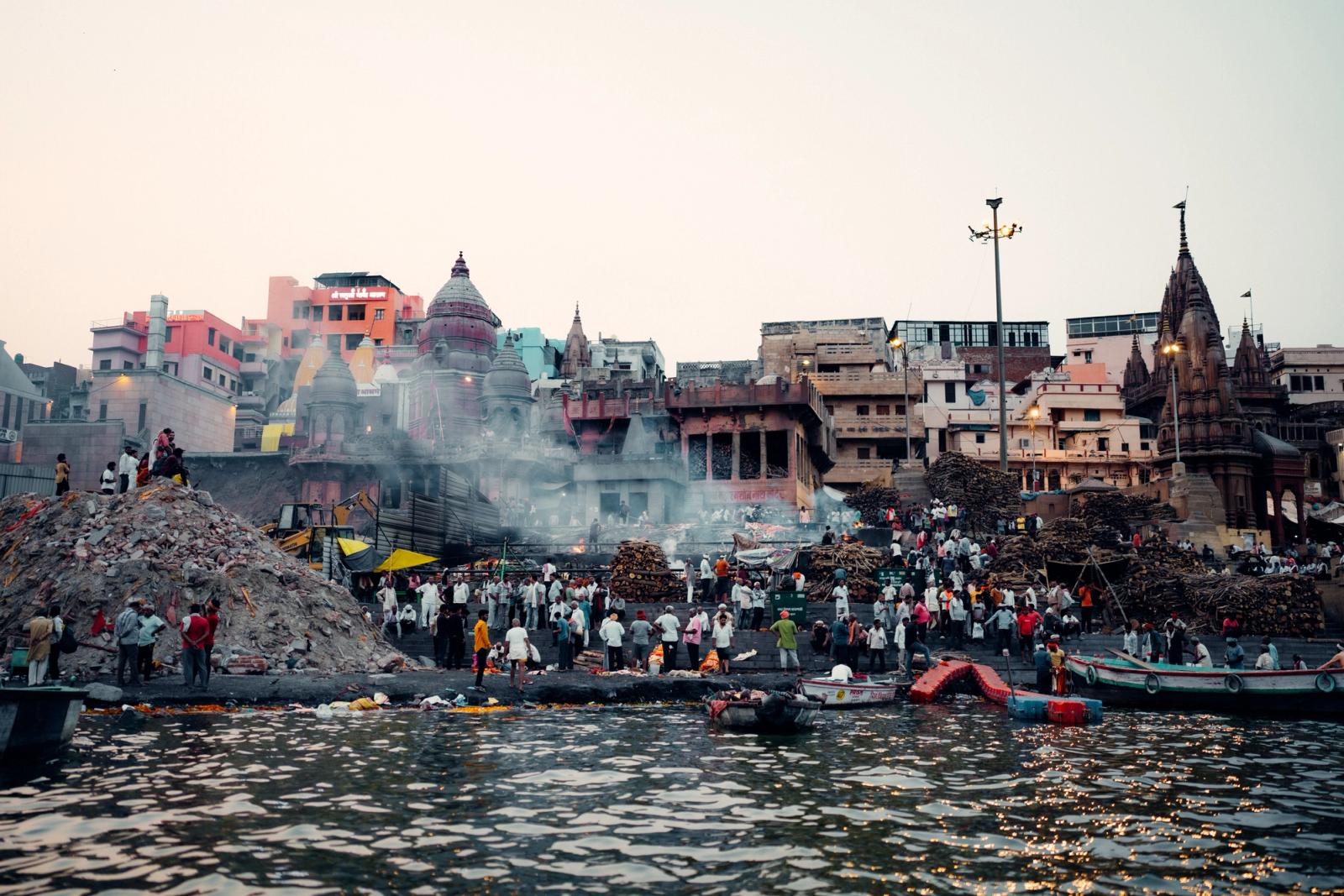 Vibrant view of Varanasi's ghats with crowds, boats, and traditional architecture by the Ganges River