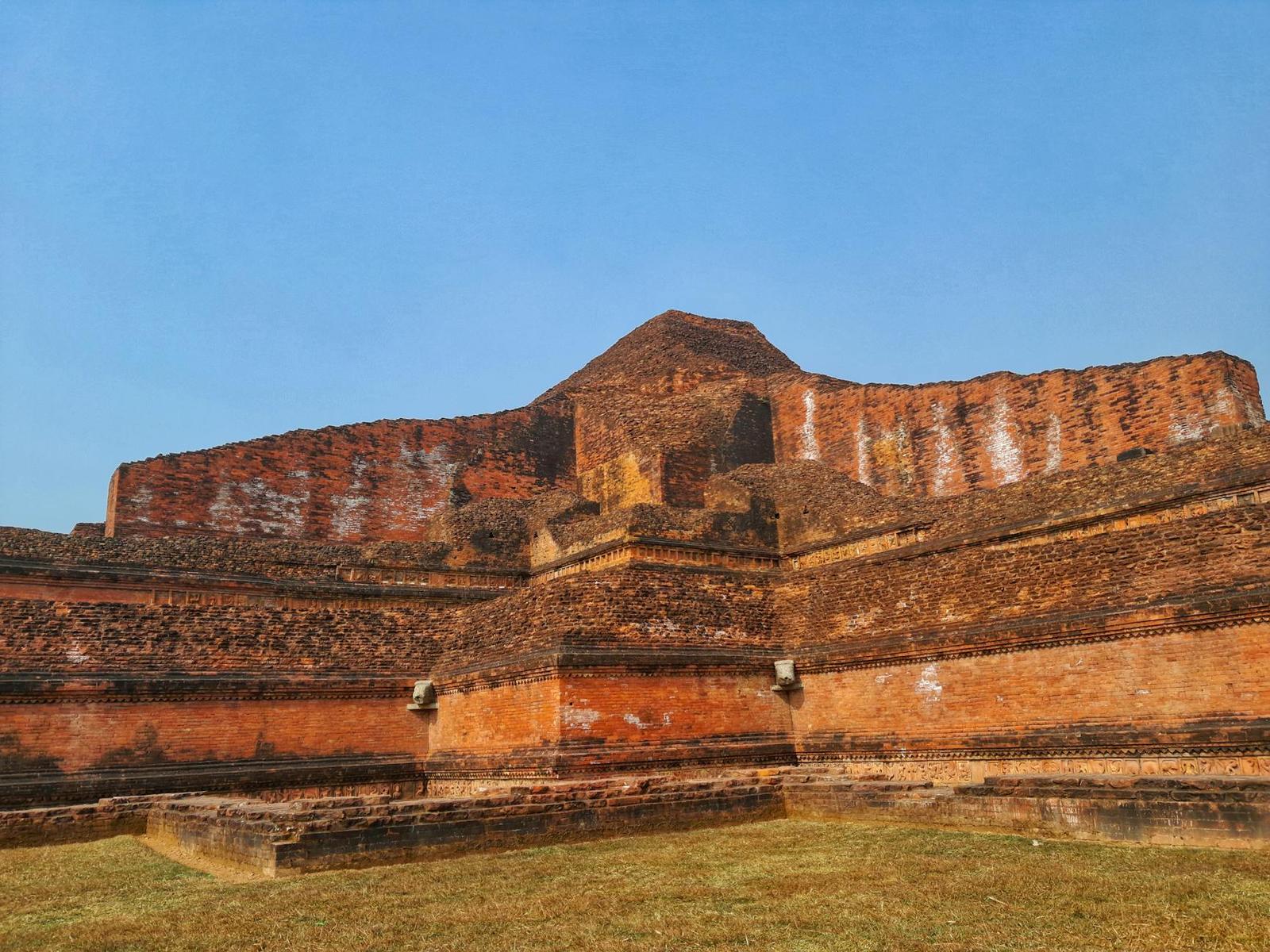 A historic brick mound stands prominently under a clear blue sky in an open field