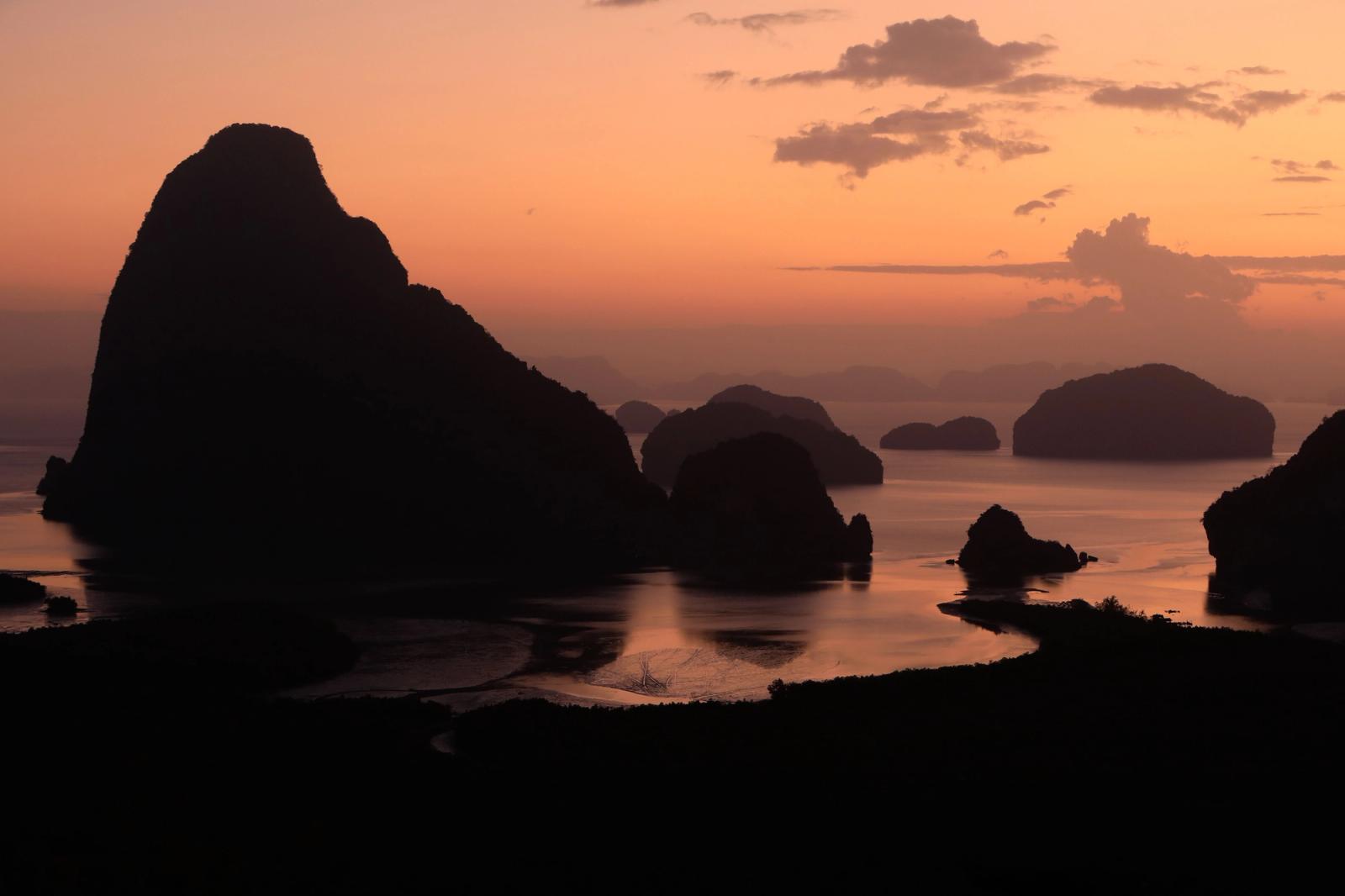Dramatic silhouettes of rock formations at sunset in Phang-nga Bay, Thailand
