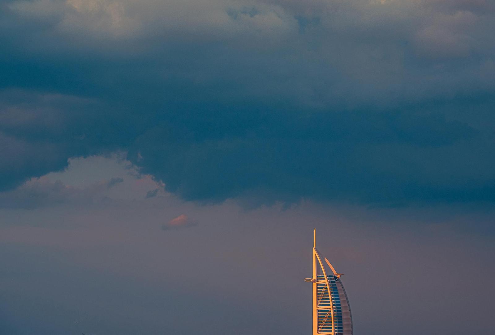 Scenic view of Burj Al Arab at sunset with dramatic cloud cover in Dubai, UAE