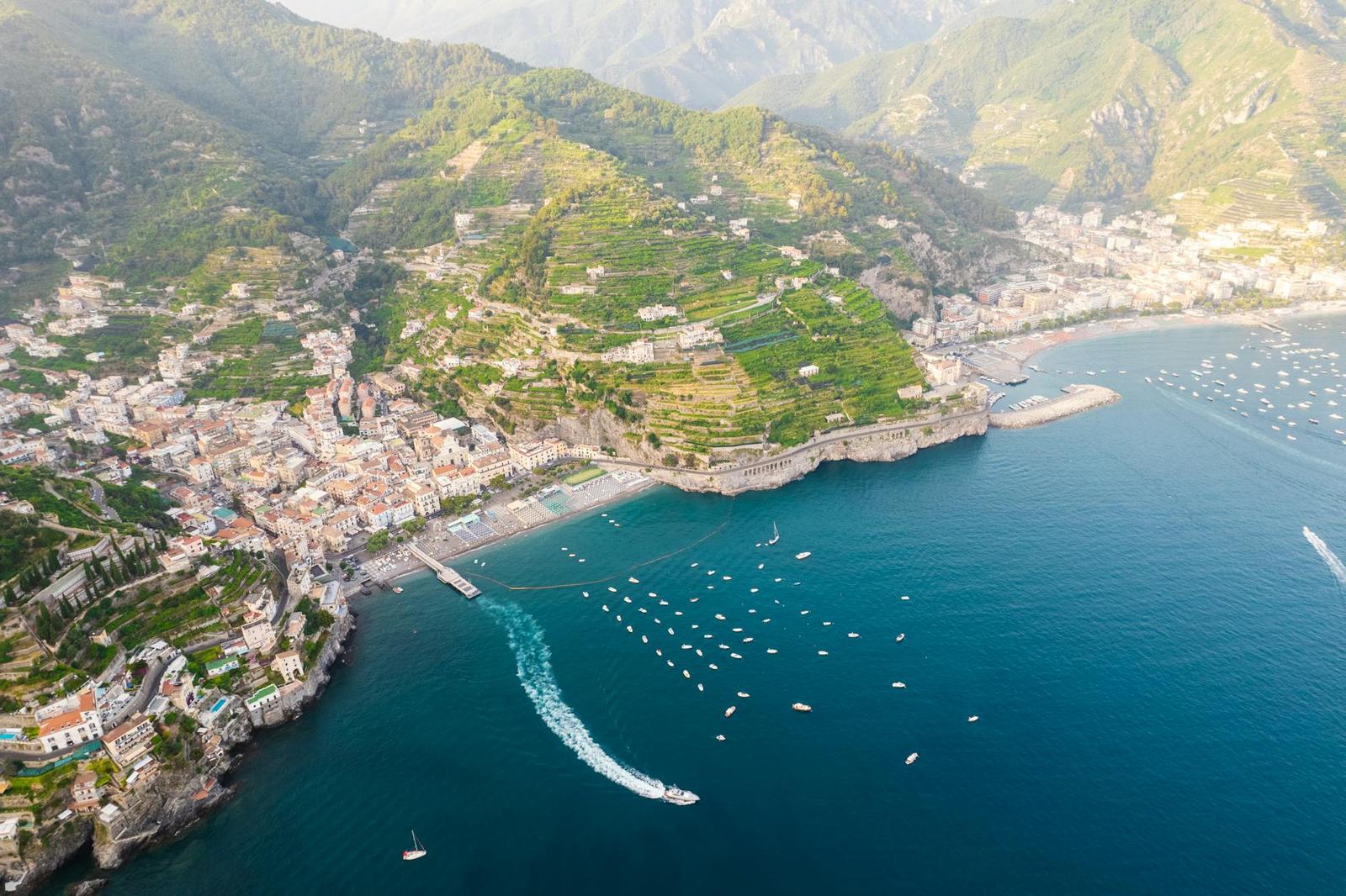Aerial view of a coastal hillside town with boats scattered across the bay