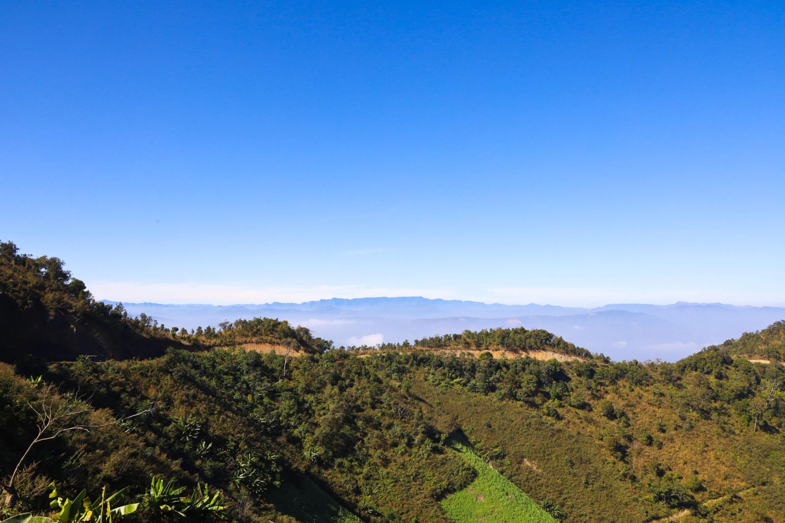 Layered green ridgelines fading into a hazy horizon under a clear sky