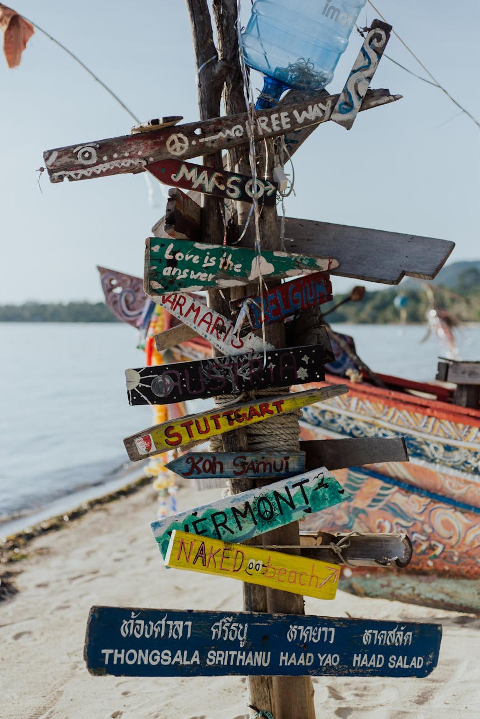 Weathered wooden signpost with hand-painted directions on a beach