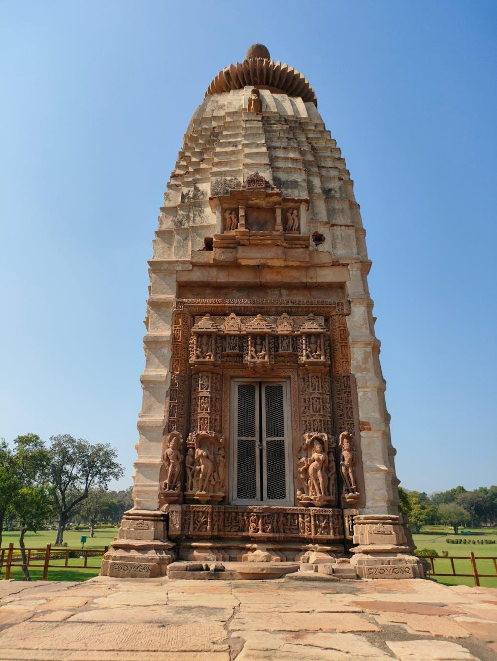 Single sandstone temple spire with carved figures around its doorway