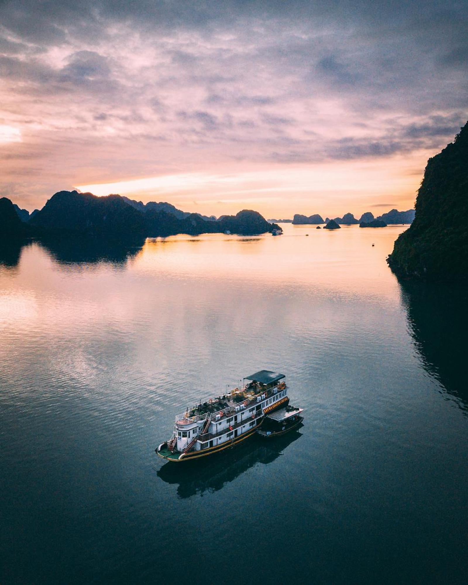 Cruise boat drifting across the bay at sunset among distant islets