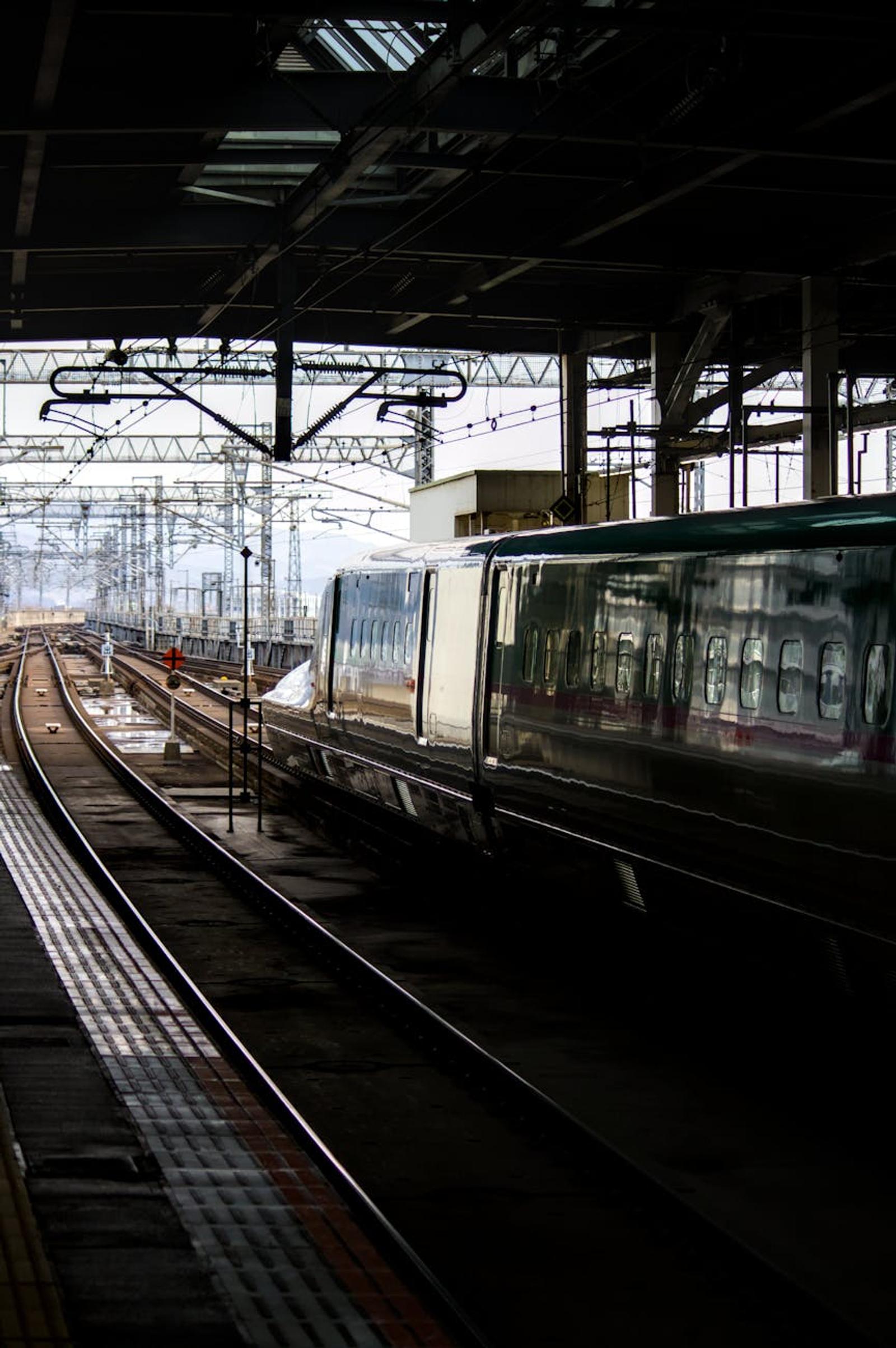 High-speed train arriving at a covered platform beneath overhead wires