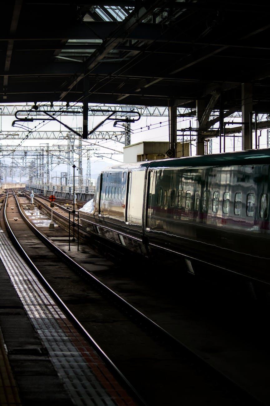 High-speed train arriving at a covered platform beneath overhead wires