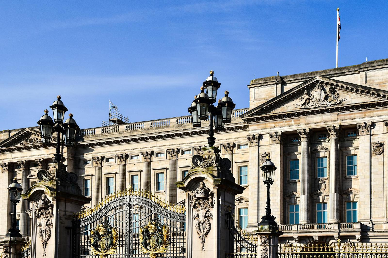 An ornate palace facade seen through gilded iron gates and lampposts