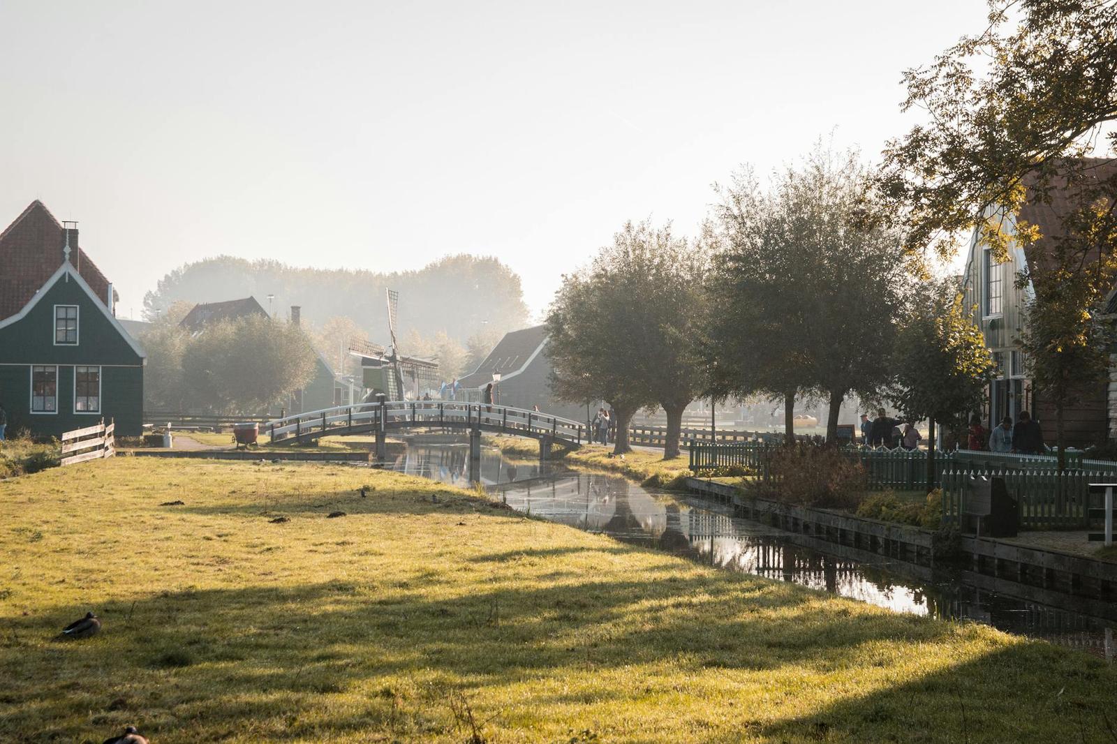 Wooden footbridge over a canal near a green timber house at sunrise