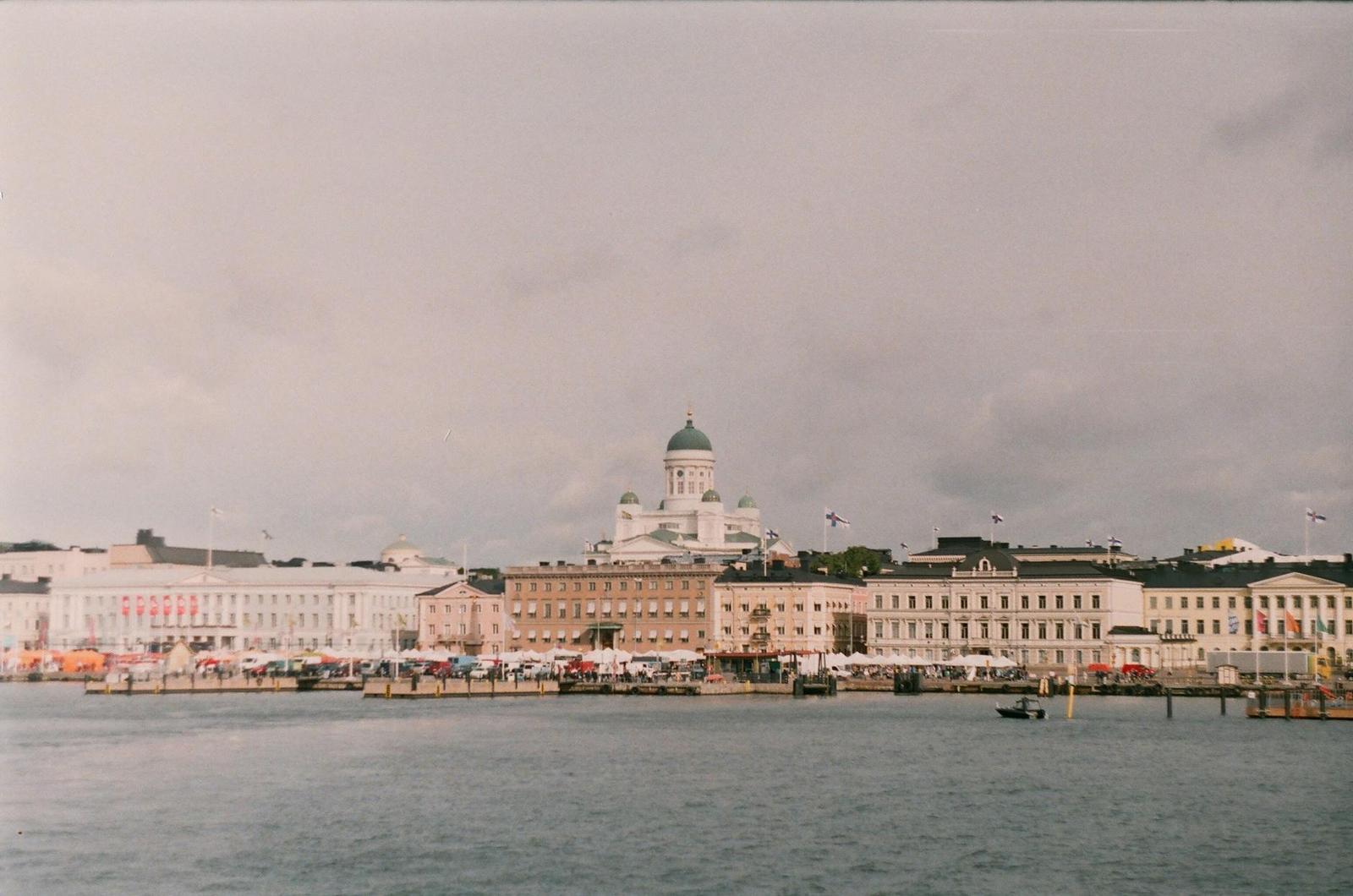 Domed cathedral rising above a harbourfront town under overcast sky