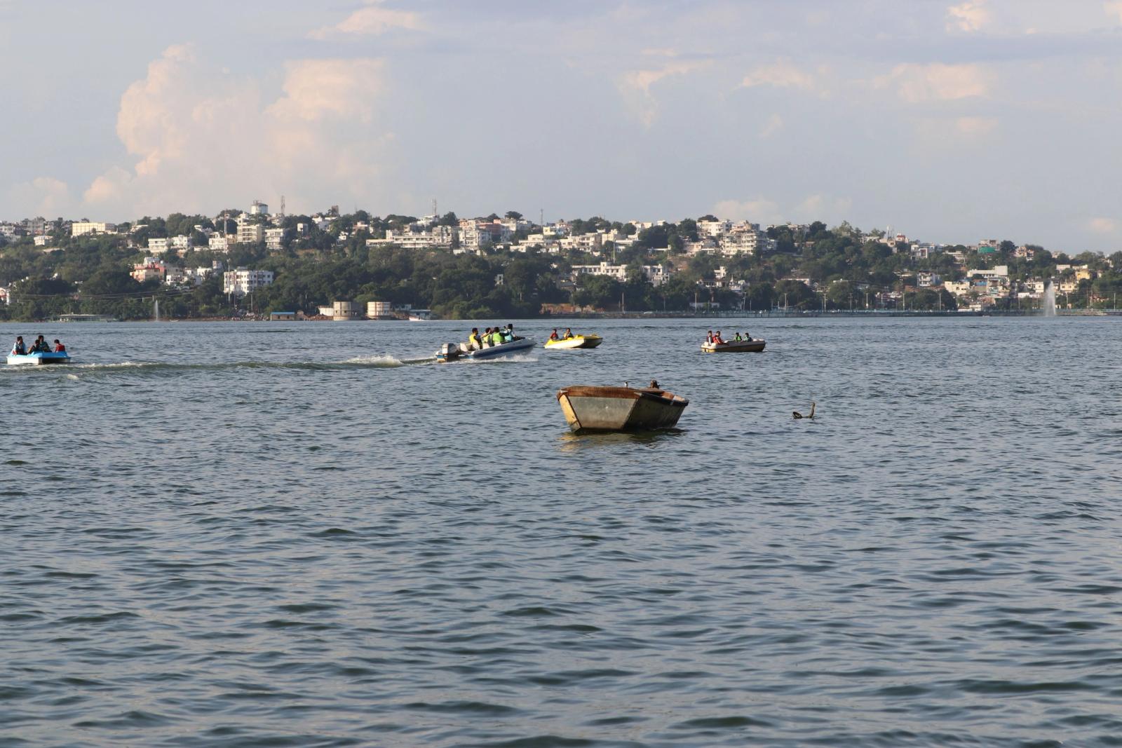Small boats crossing a lake with a hillside town on the far shore