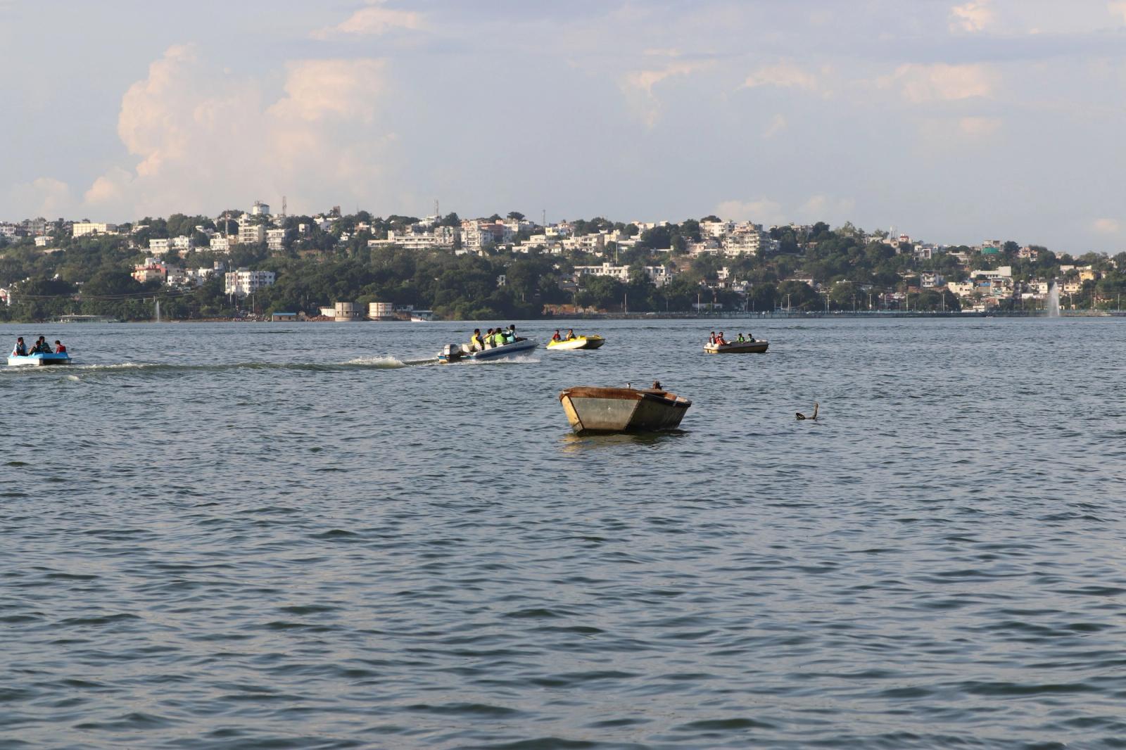 Small boats crossing a lake with a hillside town on the far shore