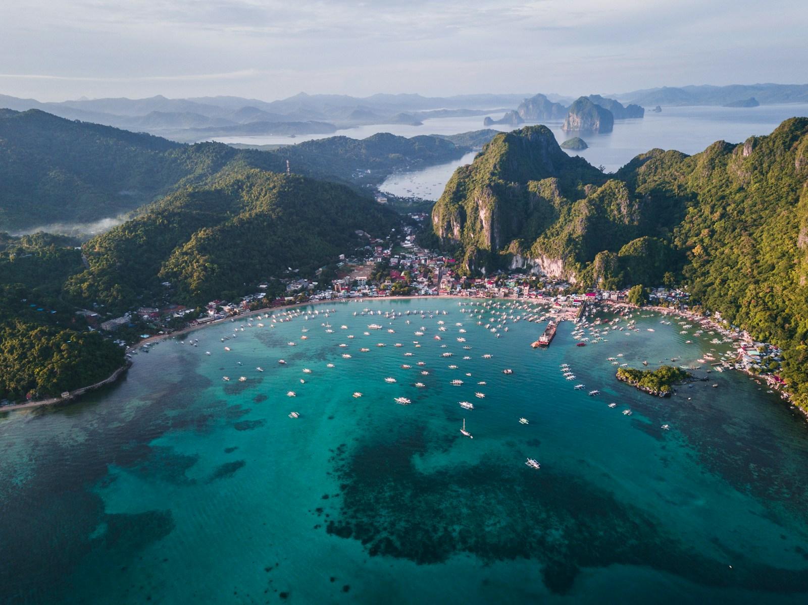 A limestone karst bay dotted with boats and fringed by jungle-covered peaks